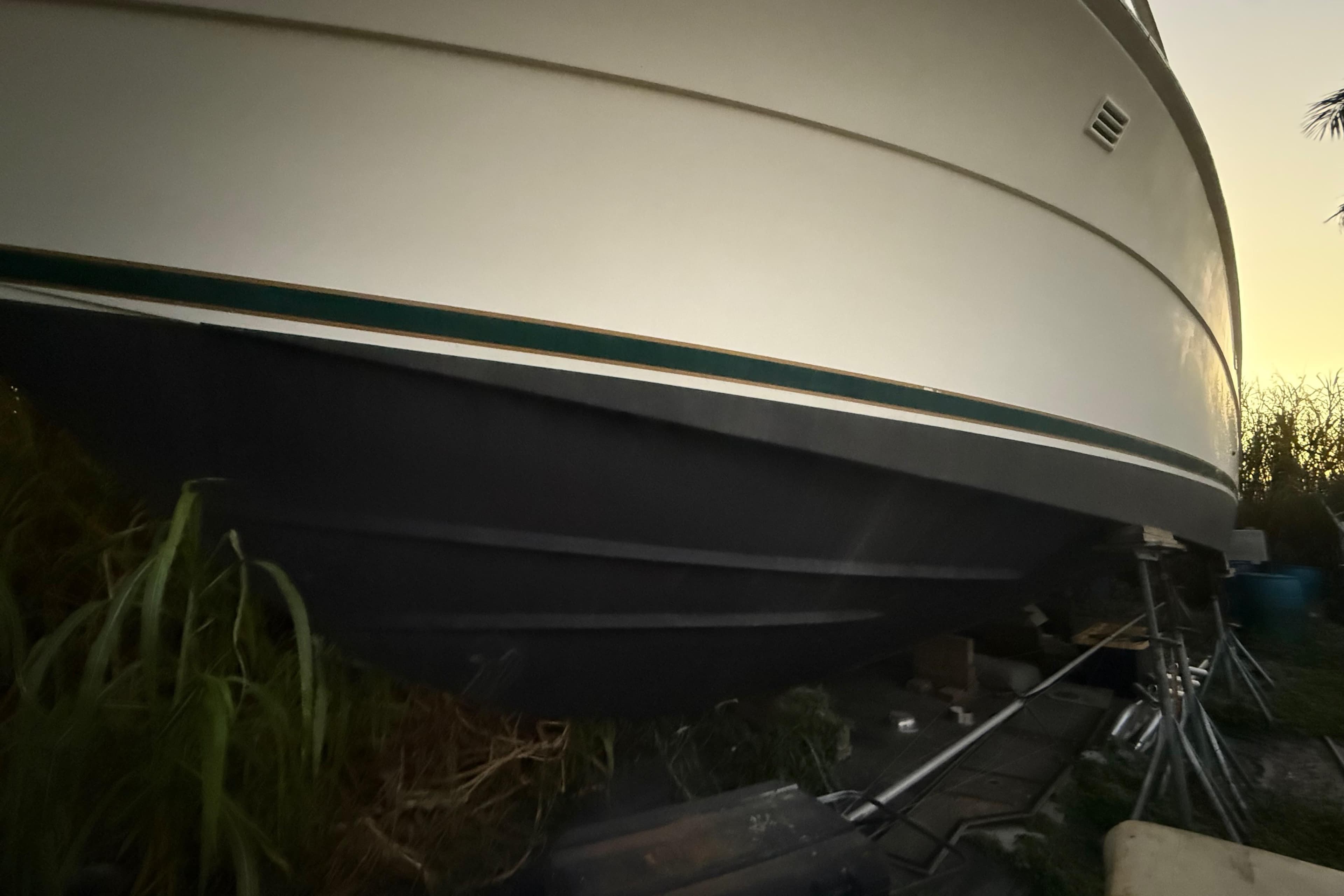 1995 Bertram 46 Moppie boat hull on stands, side view at sunset.