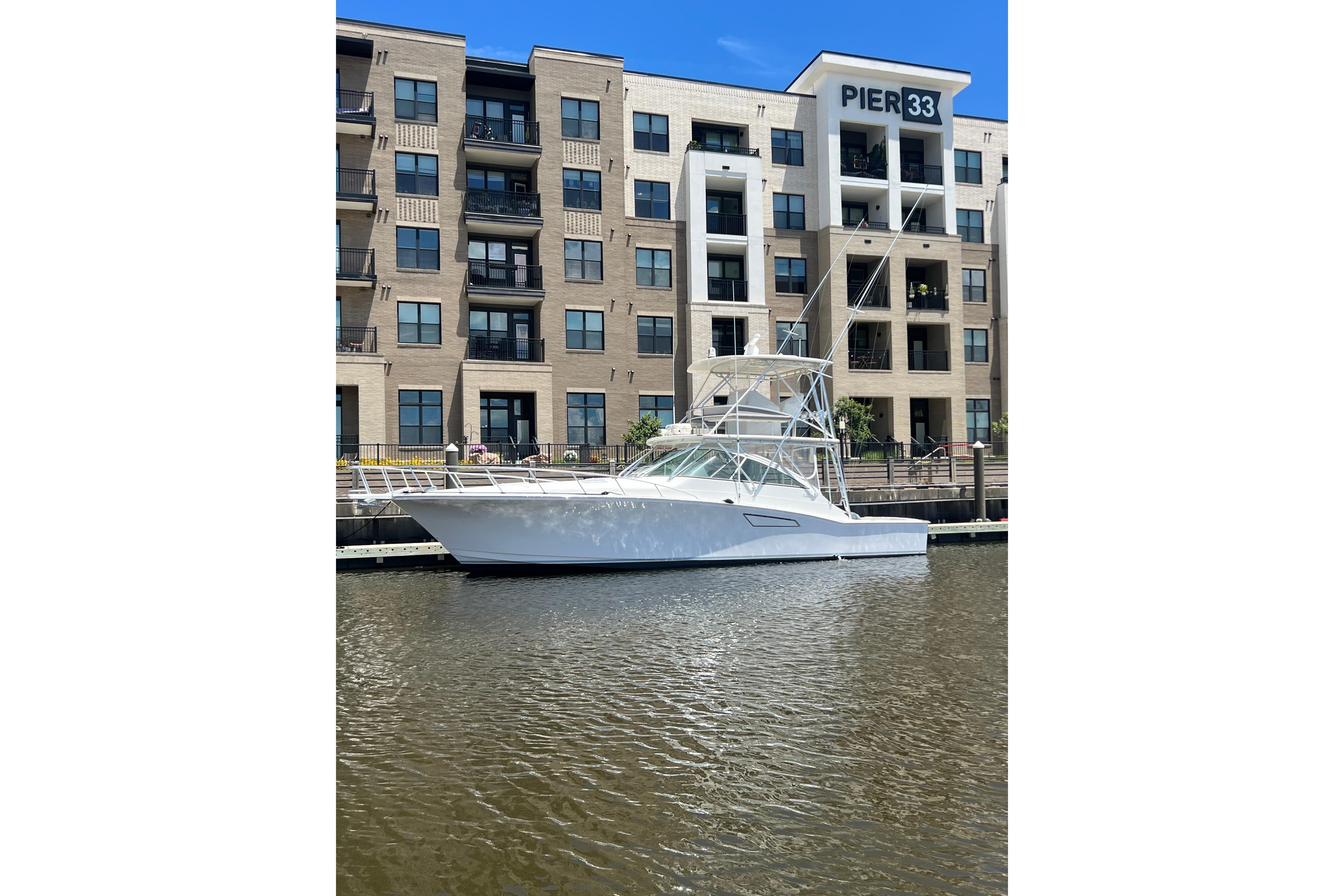 2005 Cabo 45 Express yacht docked near Pier 33, modern building backdrop.