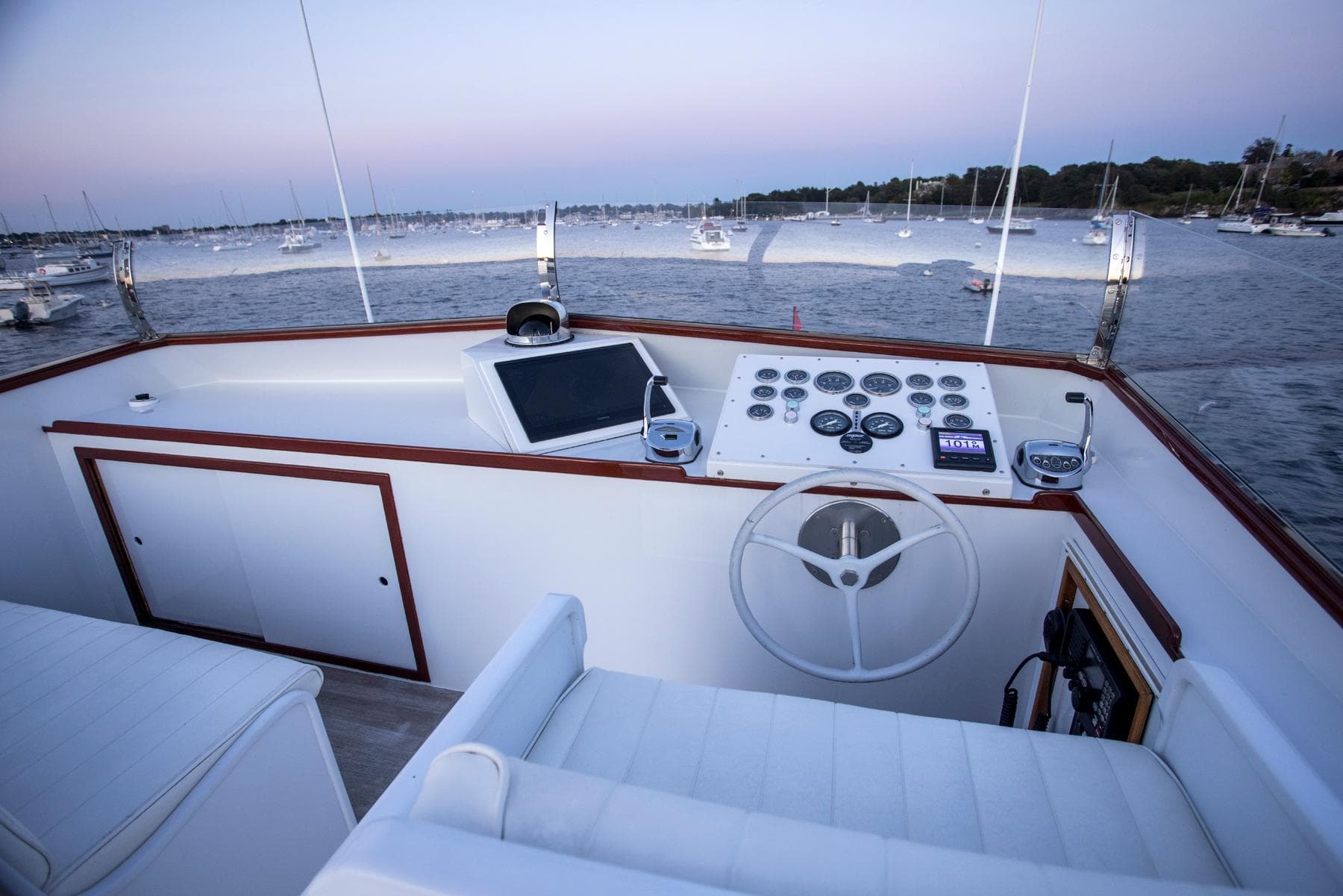 Helm of 1964 Huckins Out Islander 56 yacht with scenic harbor view.