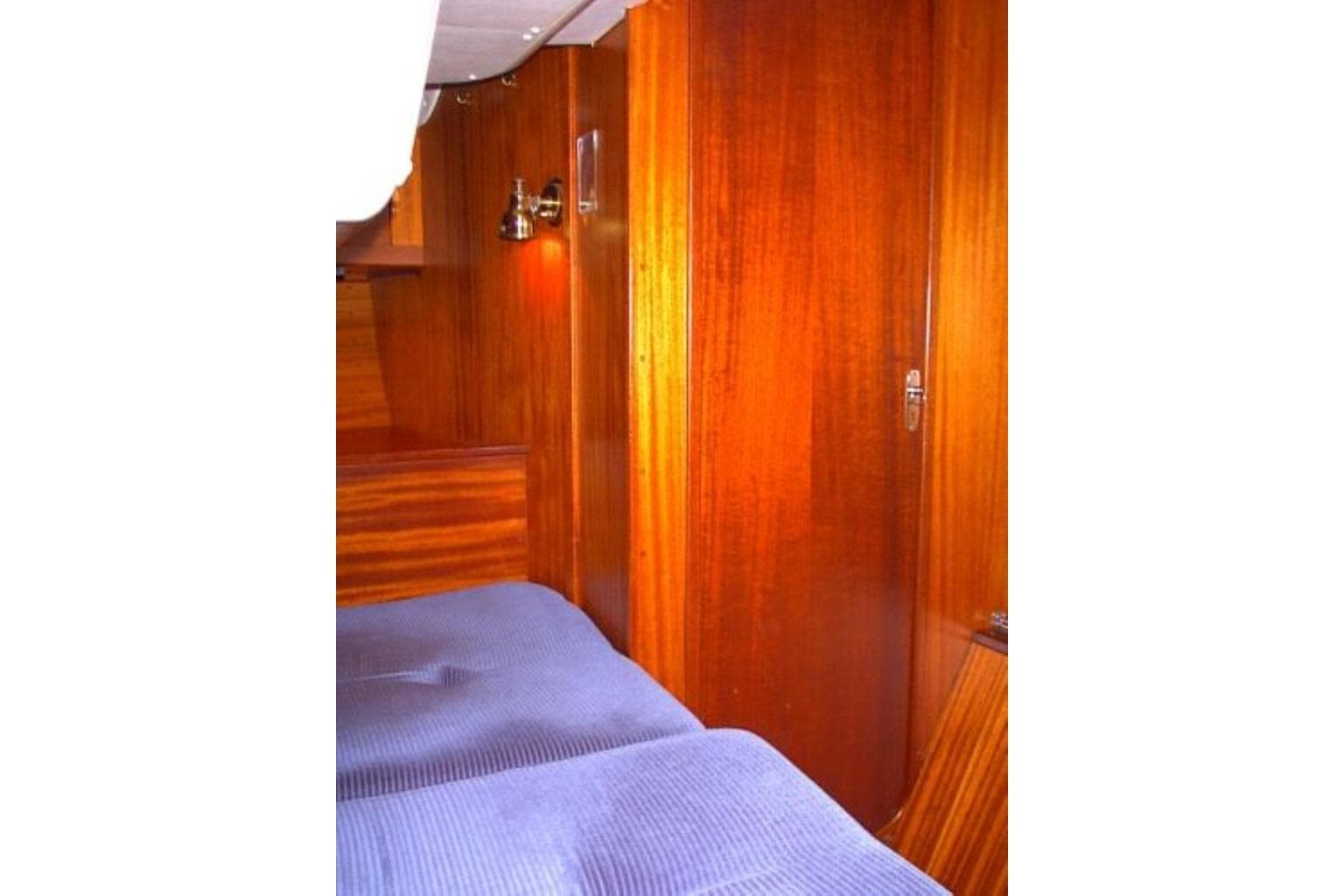Interior of 1985 Sweden Yachts 41, featuring wooden paneling and cozy bedding.