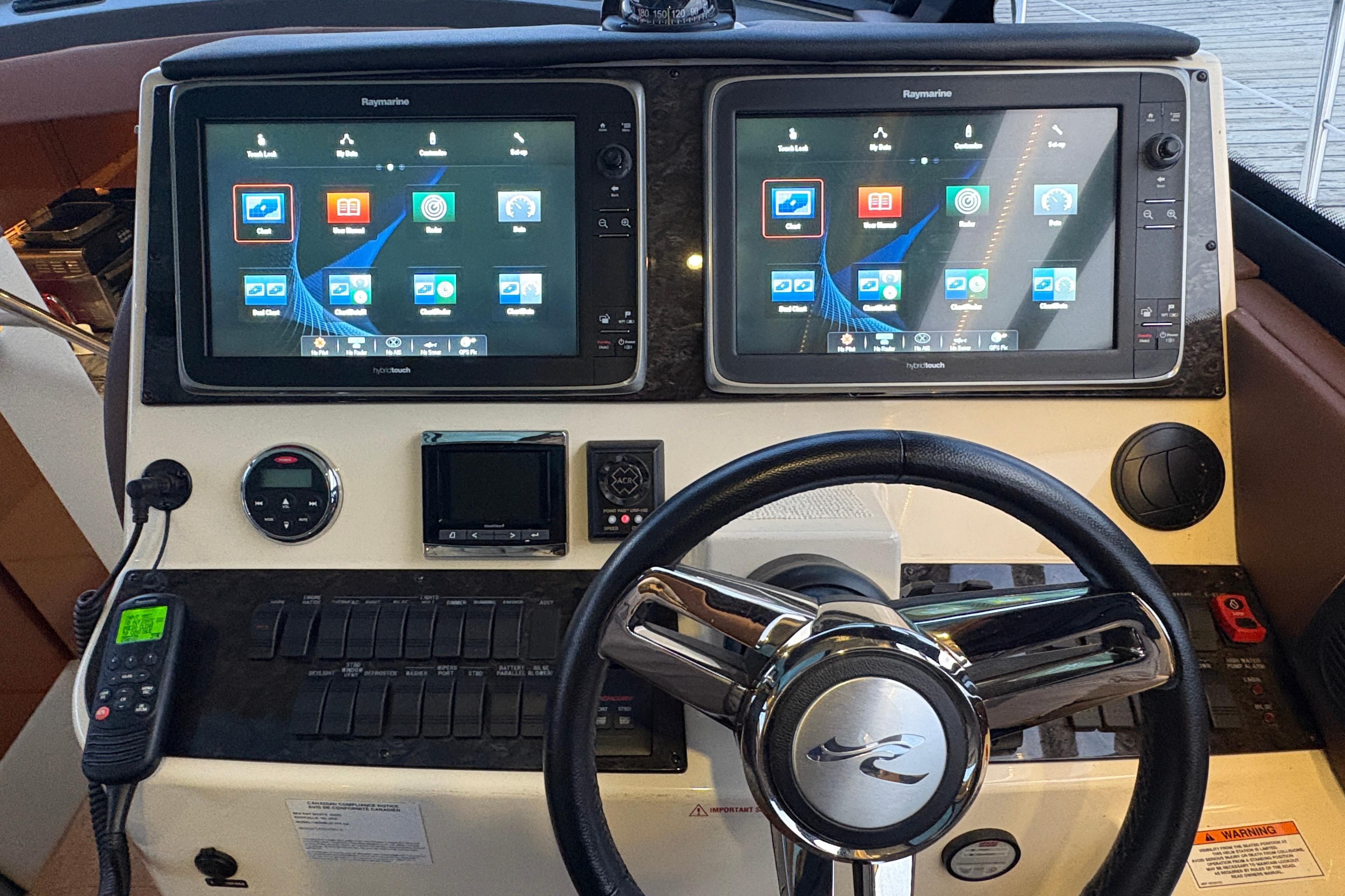 Cockpit of 2015 Sea Ray 470 Sundancer with dual Raymarine displays and steering wheel.