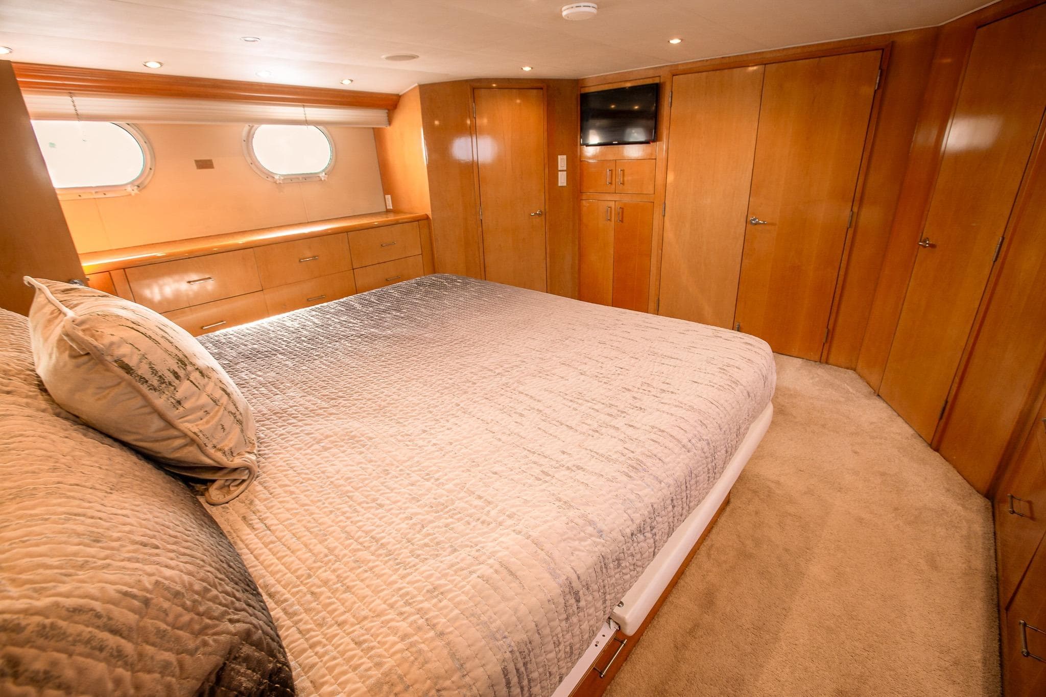 Luxurious bedroom interior of 2001 Hatteras 75 Cockpit Motor Yacht with wood paneling and cozy bedding.