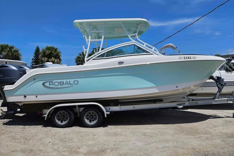 2019 Robalo R247 Dual Console boat on trailer, light blue hull, sunny day.