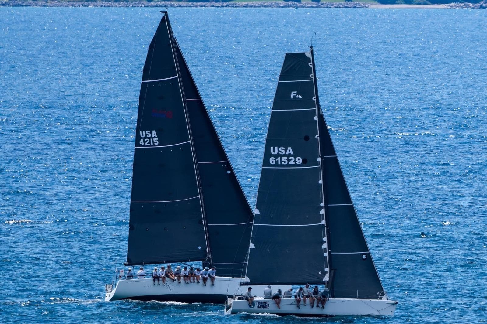 Two Farr 11s sailboats racing on the ocean, 2009 models, with crews on board.