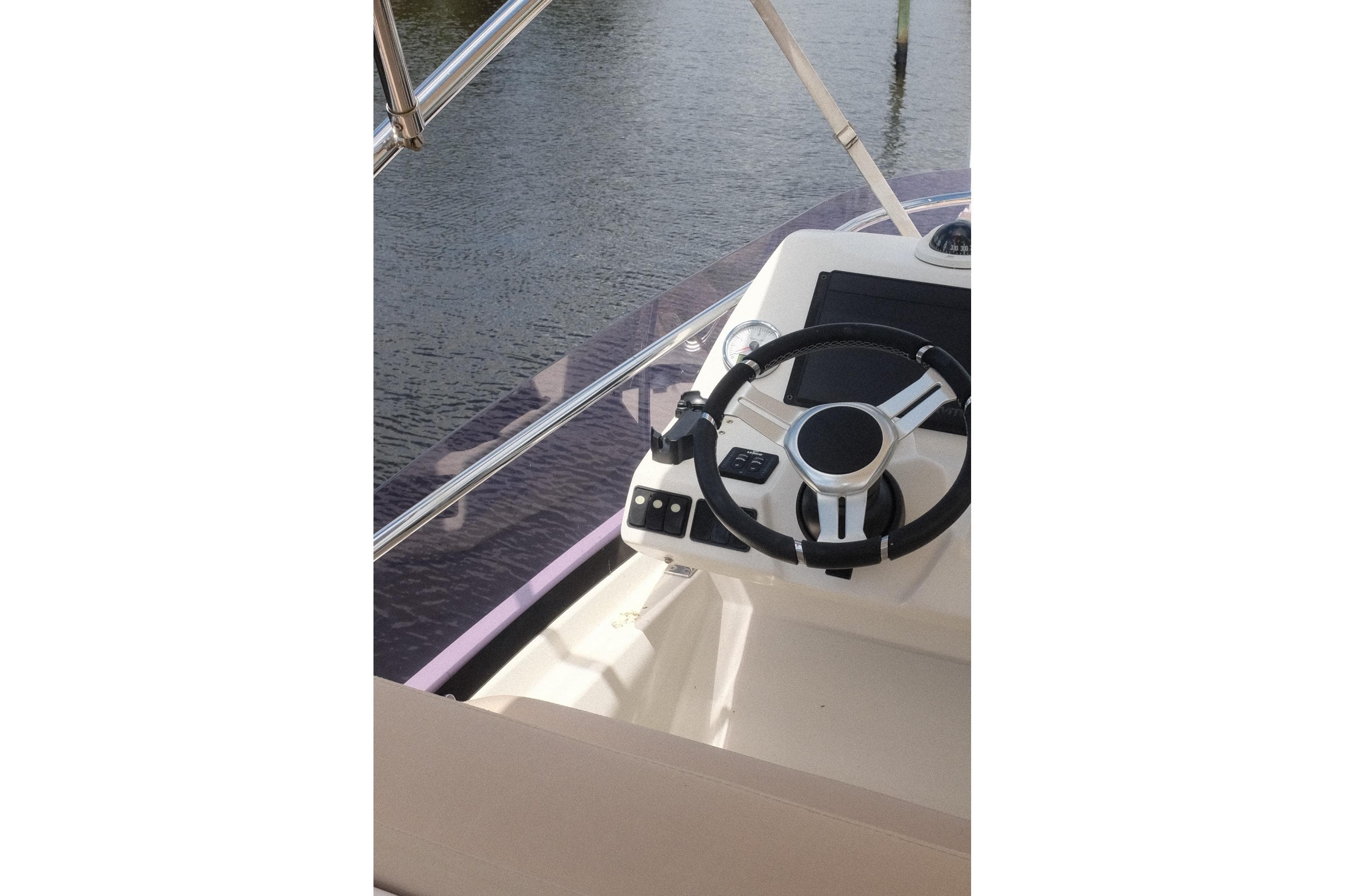 Steering wheel of a 2016 Prestige 500 yacht, overlooking calm waters.