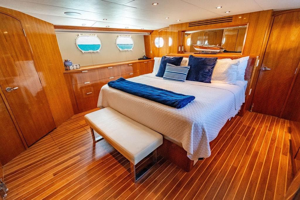 Luxurious bedroom interior of 2003 Hatteras 75' Cockpit MY yacht with wood finish.