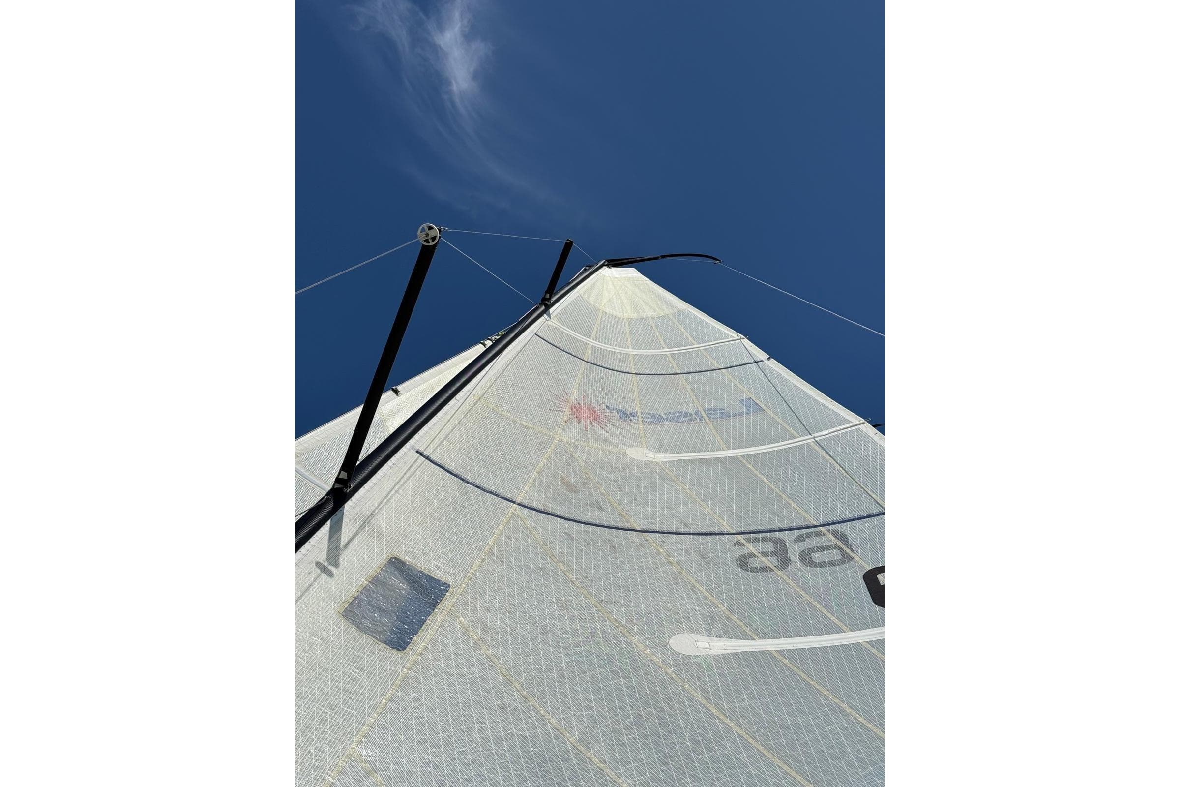 Sailboat mast and sail against clear blue sky, Laser SB3, 2003 model.