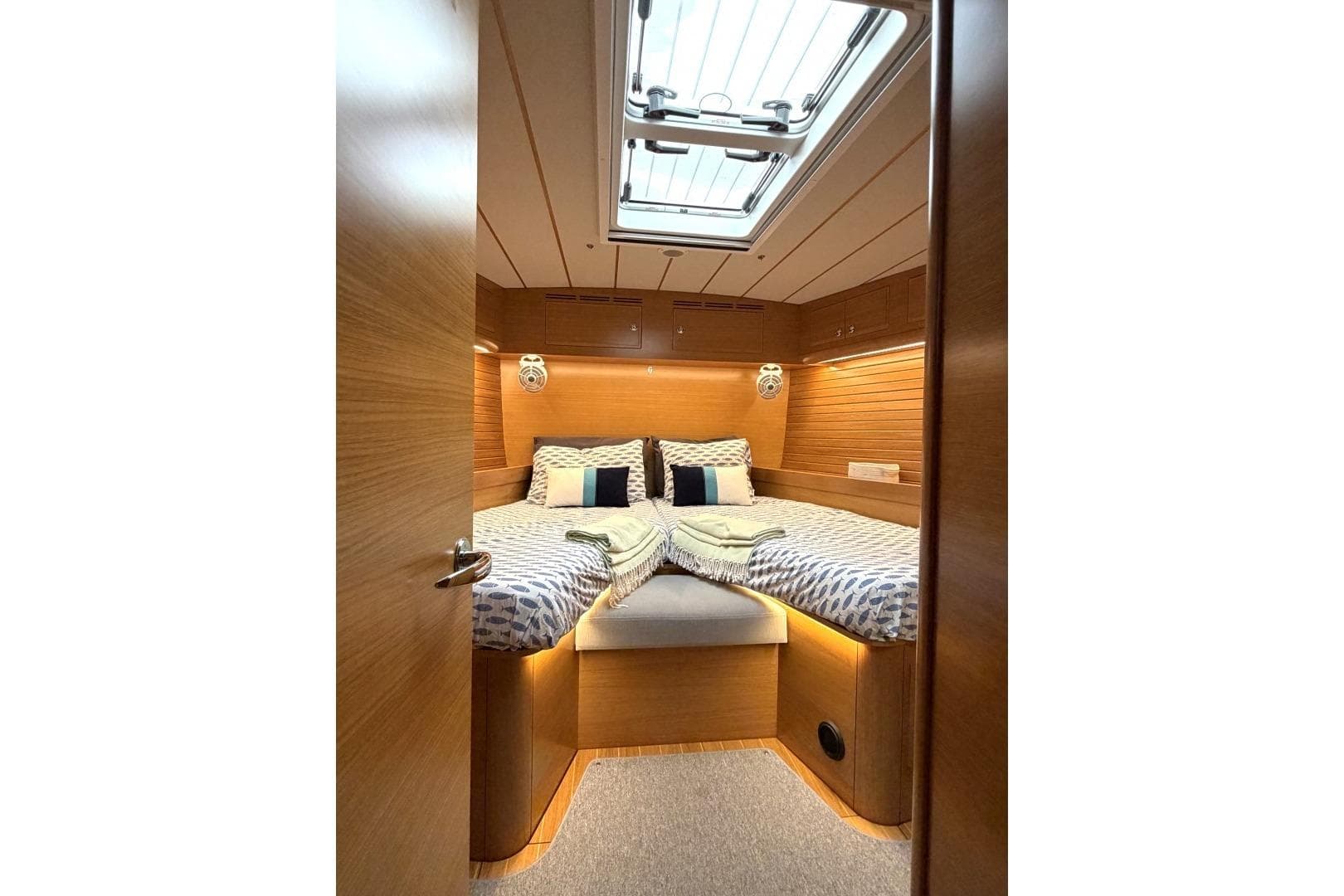 Luxurious cabin interior of 2023 Hallberg-Rassy 57 yacht with cozy bedding and skylight.