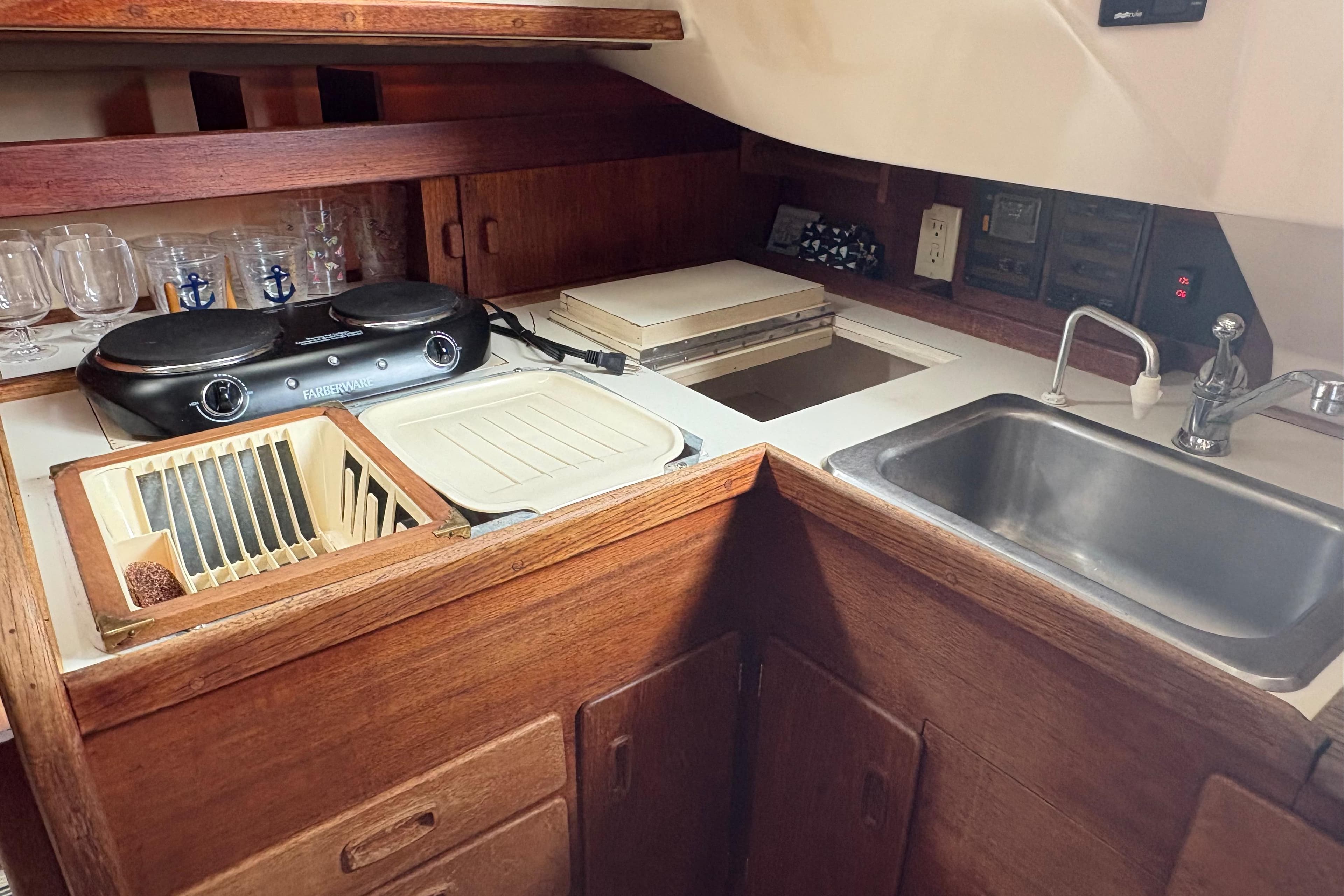 1981 Sabre 31 yacht kitchen with stove, sink, and wooden cabinetry.