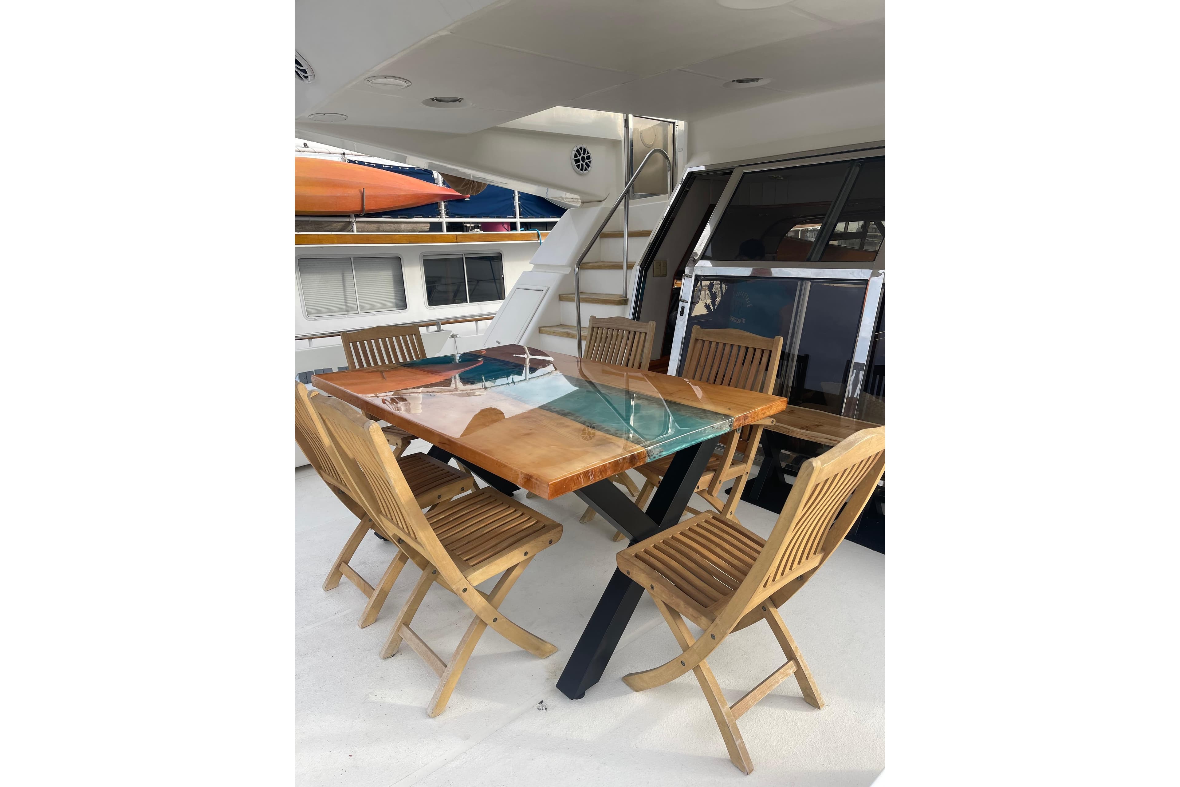 Outdoor dining area on 1994 Johnson High-Tech 65 Euro yacht with wooden table and chairs.