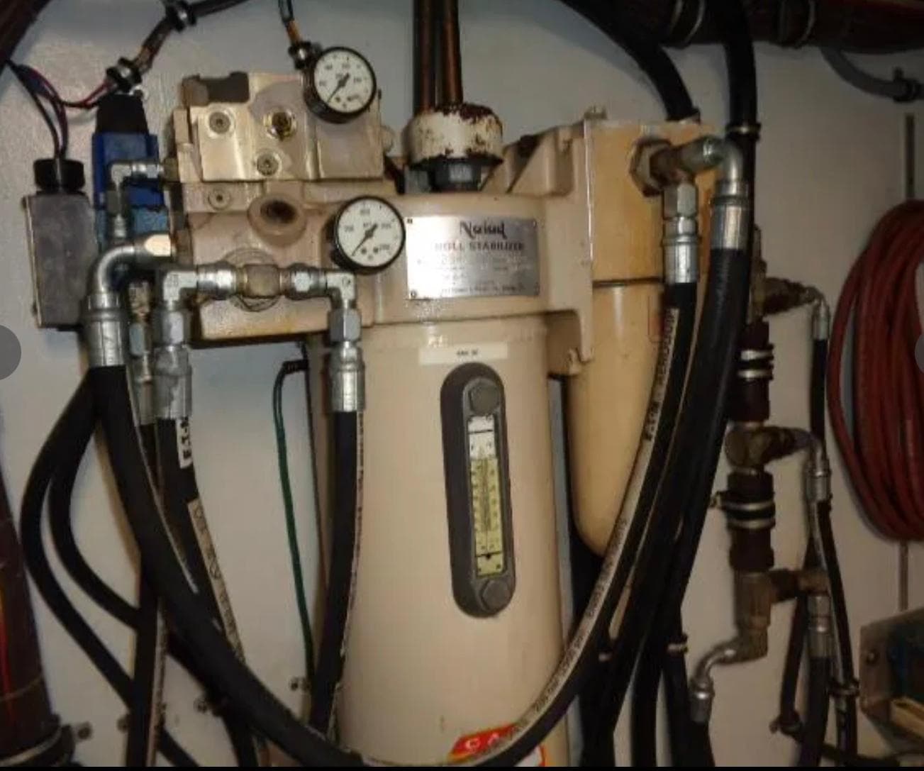 Engine room equipment on 1989 Hatteras 67 Cockpit Motor Yacht, featuring gauges and hoses.