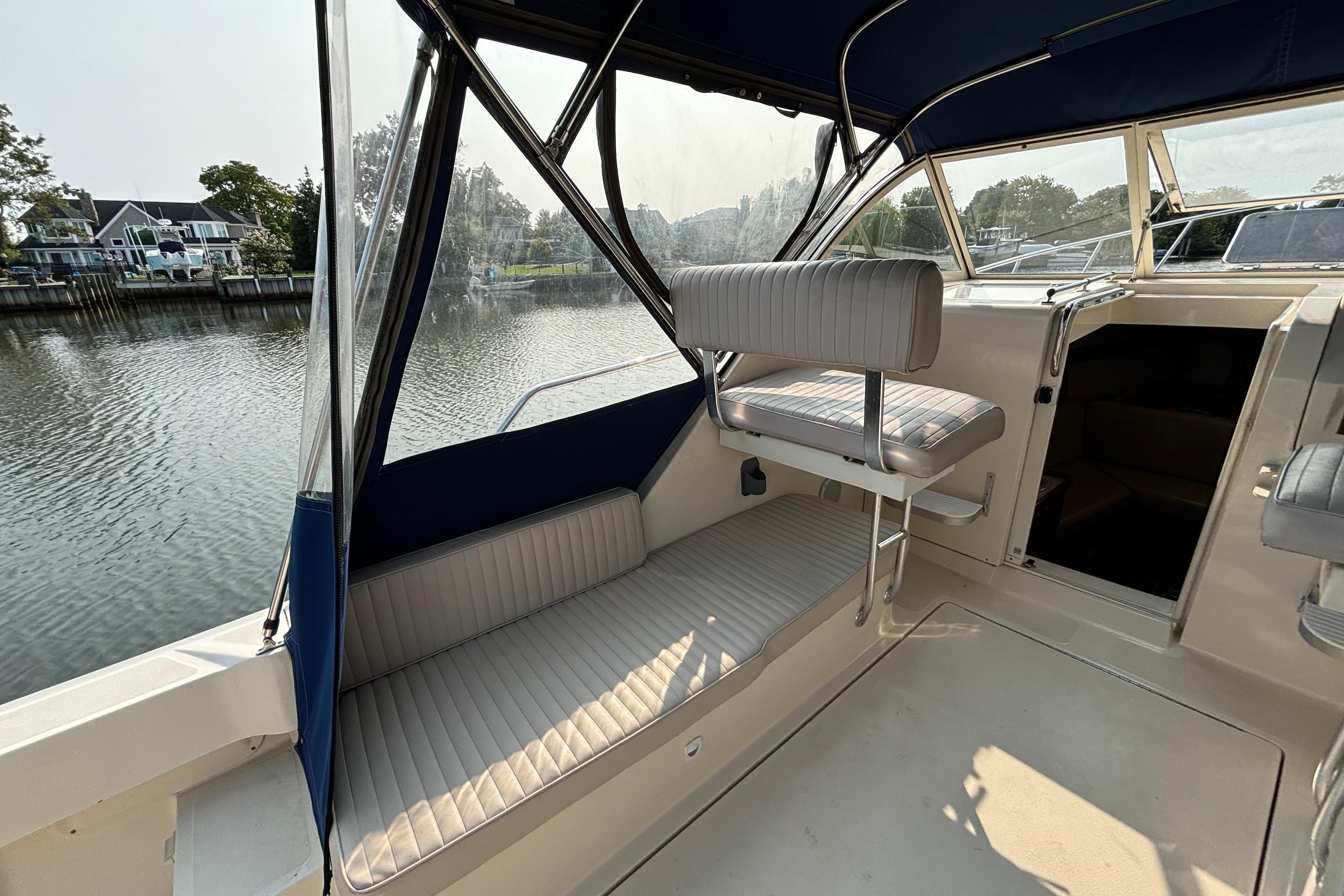 2005 Mainship Pilot 30-II Sedan interior with seating, docked by a serene waterfront.