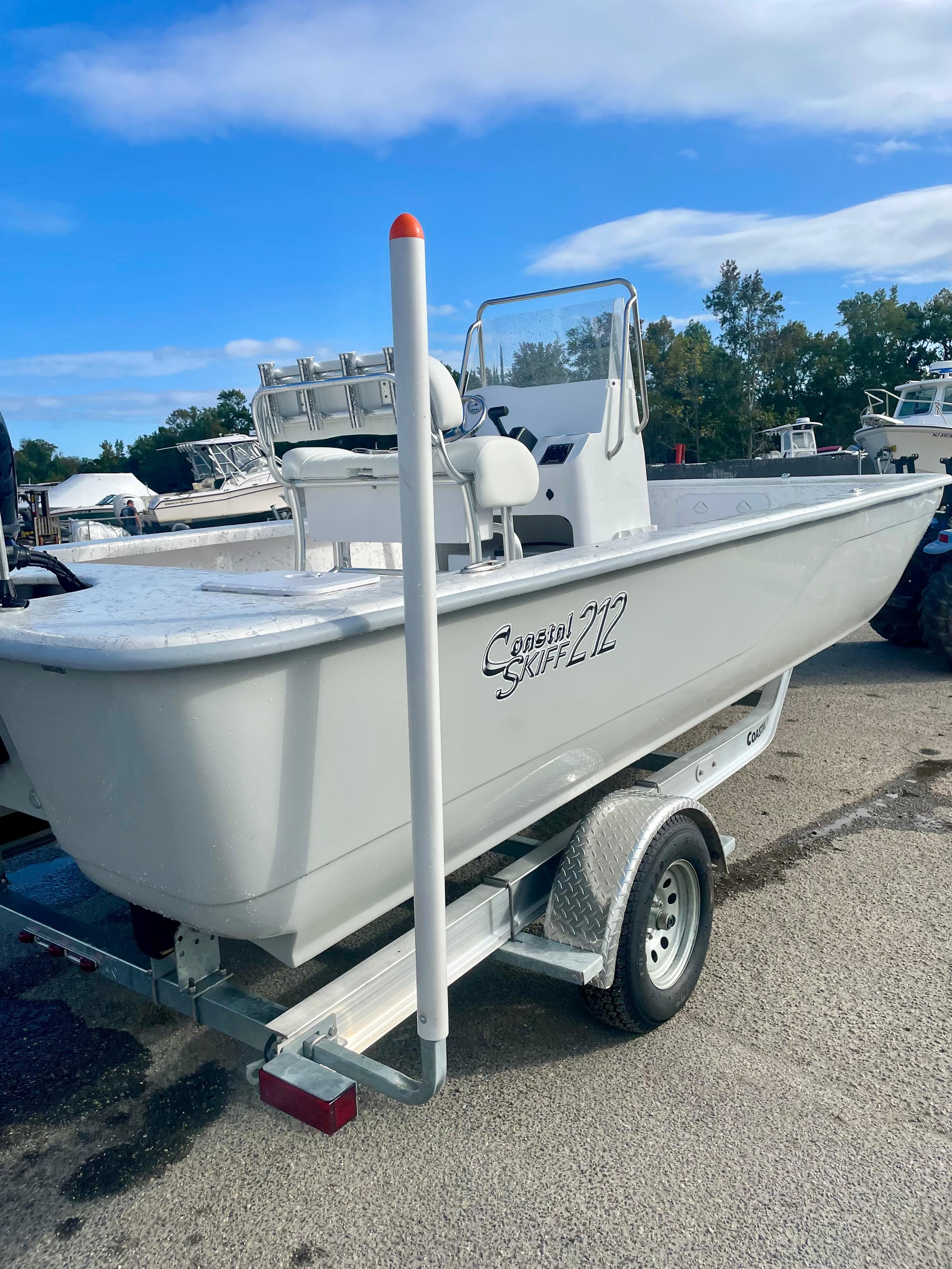2025 Coastal Skiff 212 boat on trailer, parked outdoors under blue sky.