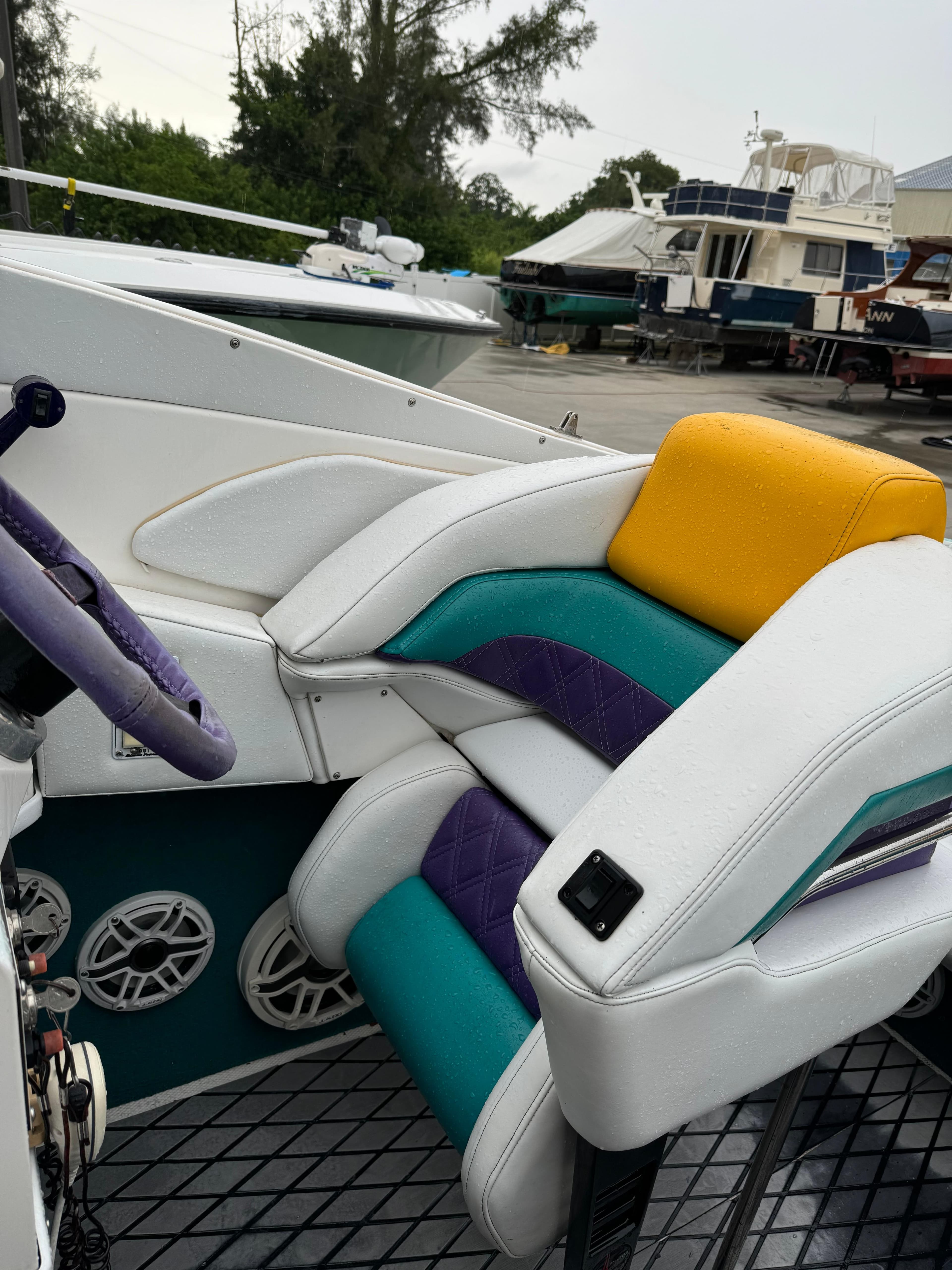 1997 Hustler 32 boat interior with colorful seats and steering wheel.