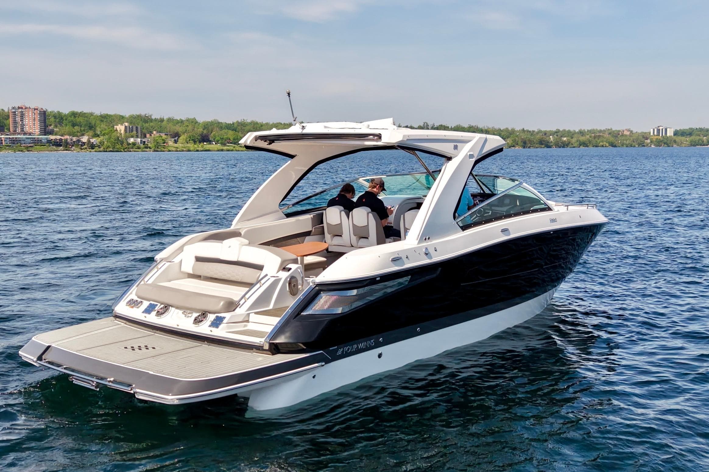 2018 Four Winns H350 boat cruising on a serene lake under a clear sky.