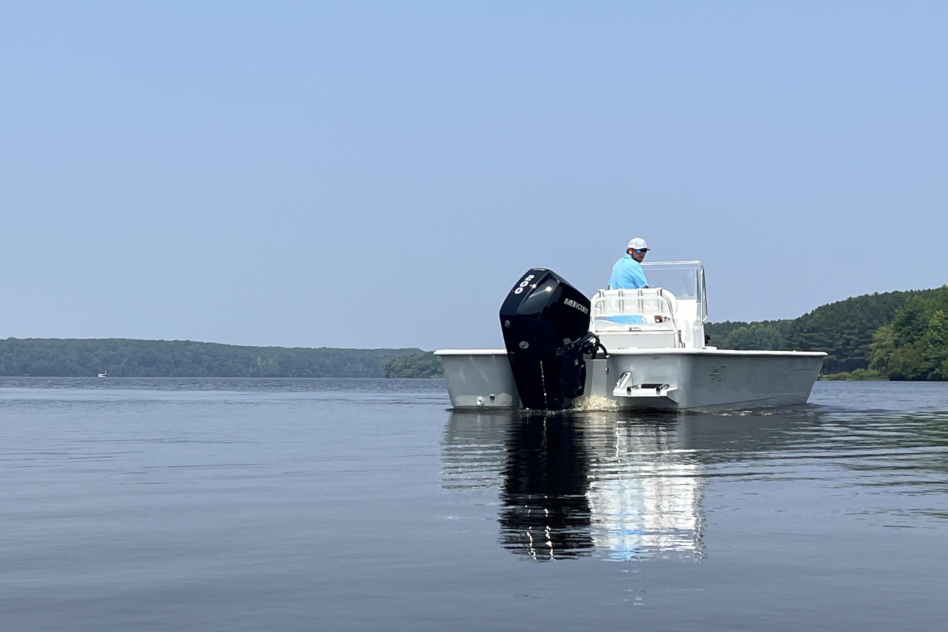 2024 Coastal Skiff 271 boat on calm water with a person at the helm.