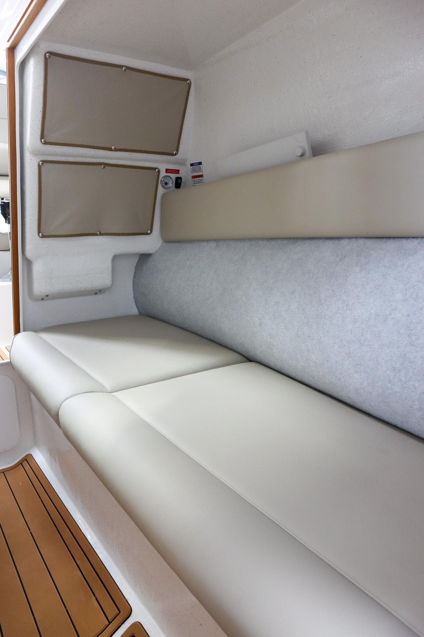 Interior of 2025 Protector 310 Targa boat with cushioned seating and wooden flooring.