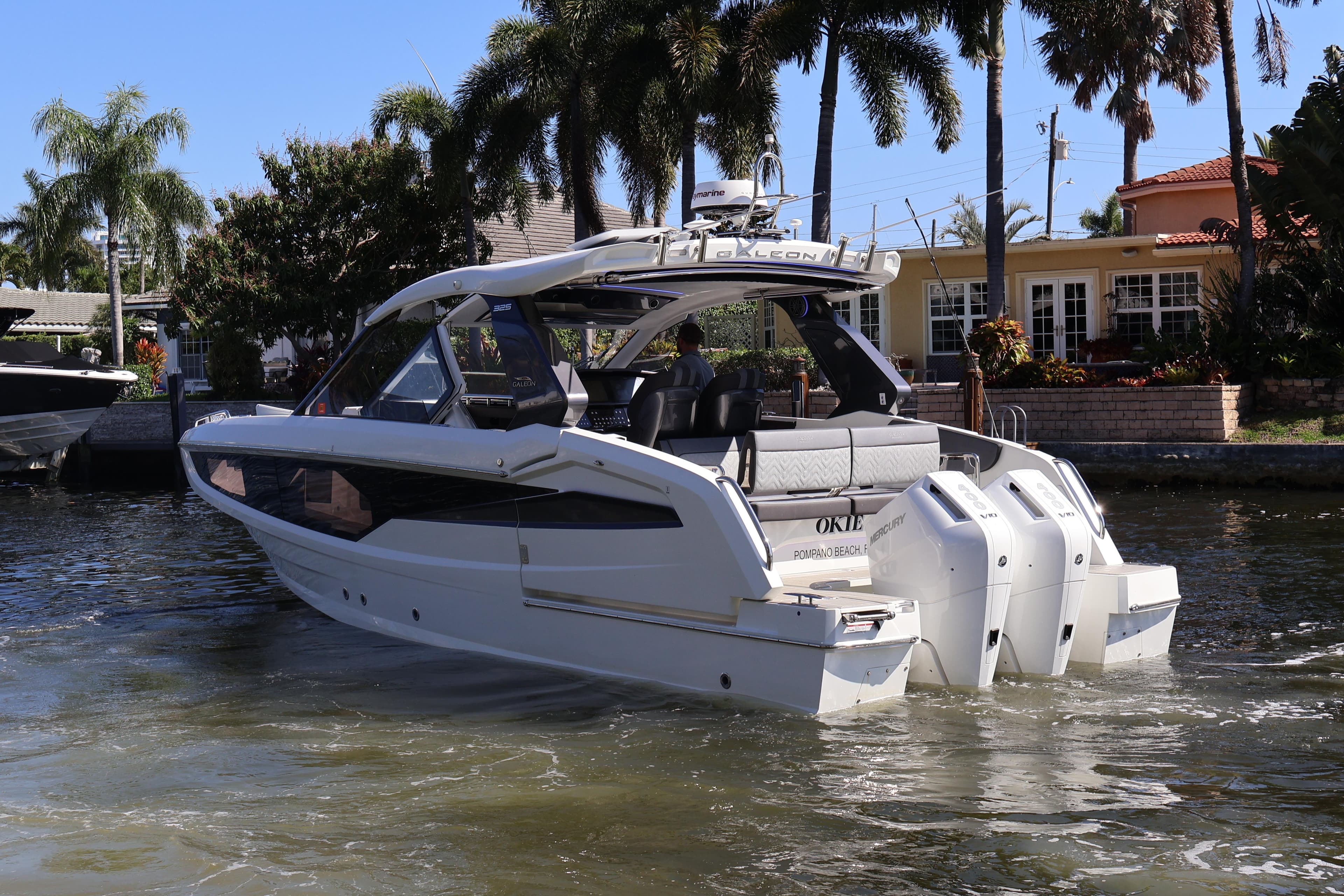 2024 Galeon 325 GTO luxury yacht cruising near waterfront homes and palm trees.