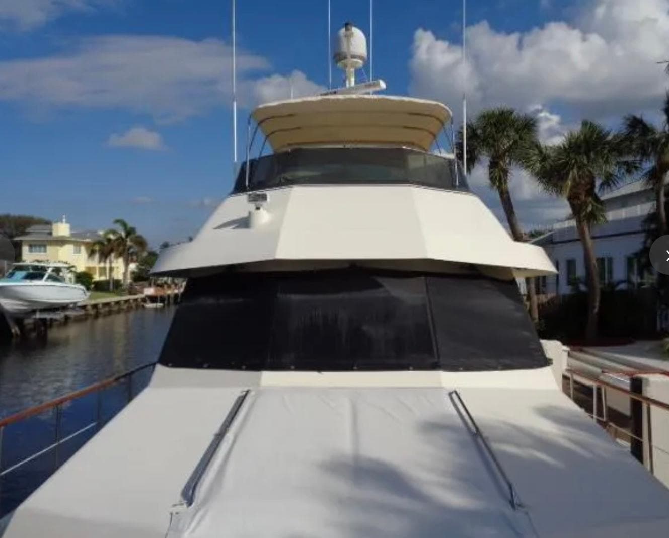 1989 Hatteras 67 Cockpit Motor Yacht docked by palm trees under blue sky.