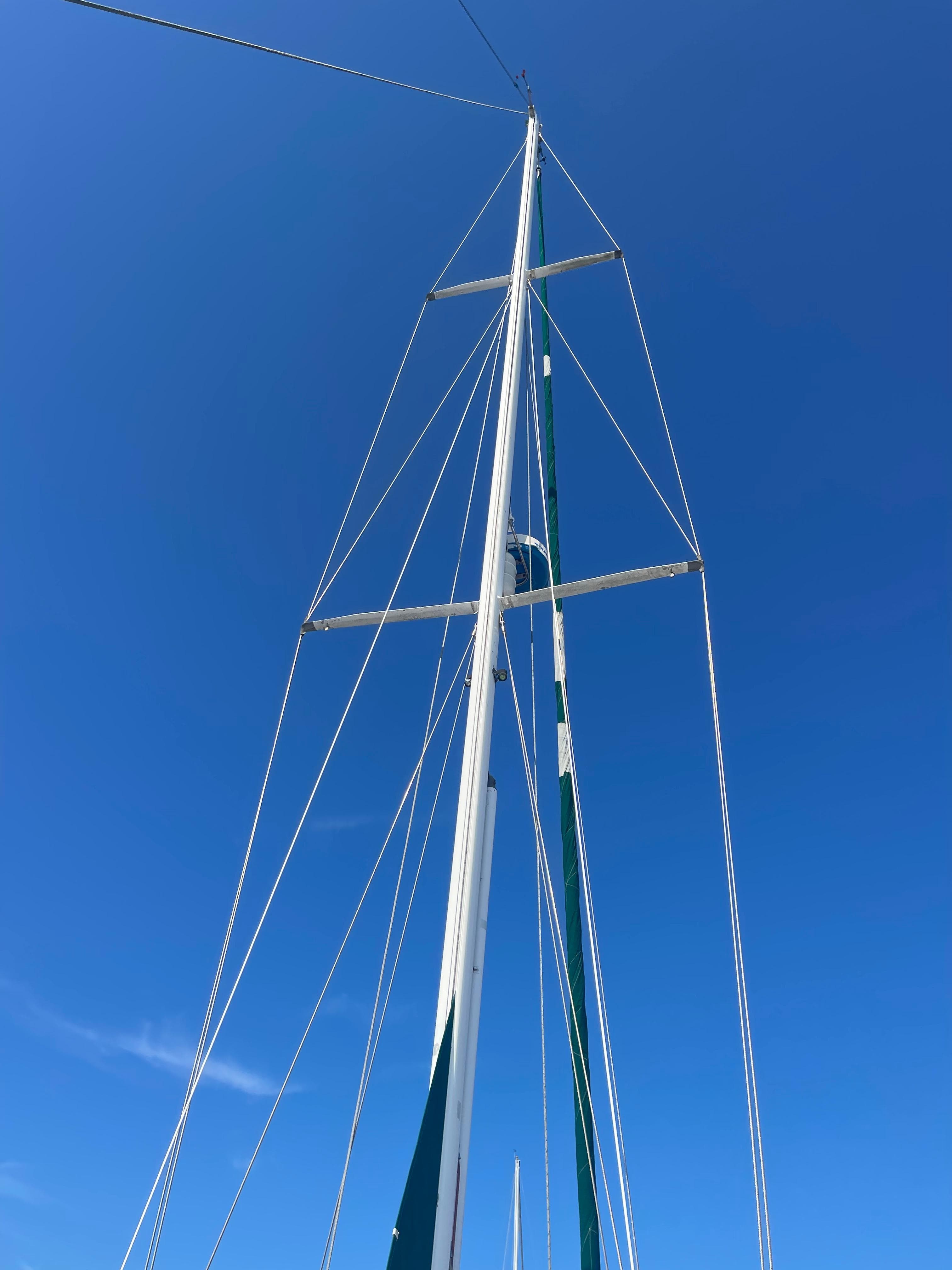 Mast of a 1995 Passport 47 AC Plan B sailboat against a clear blue sky.