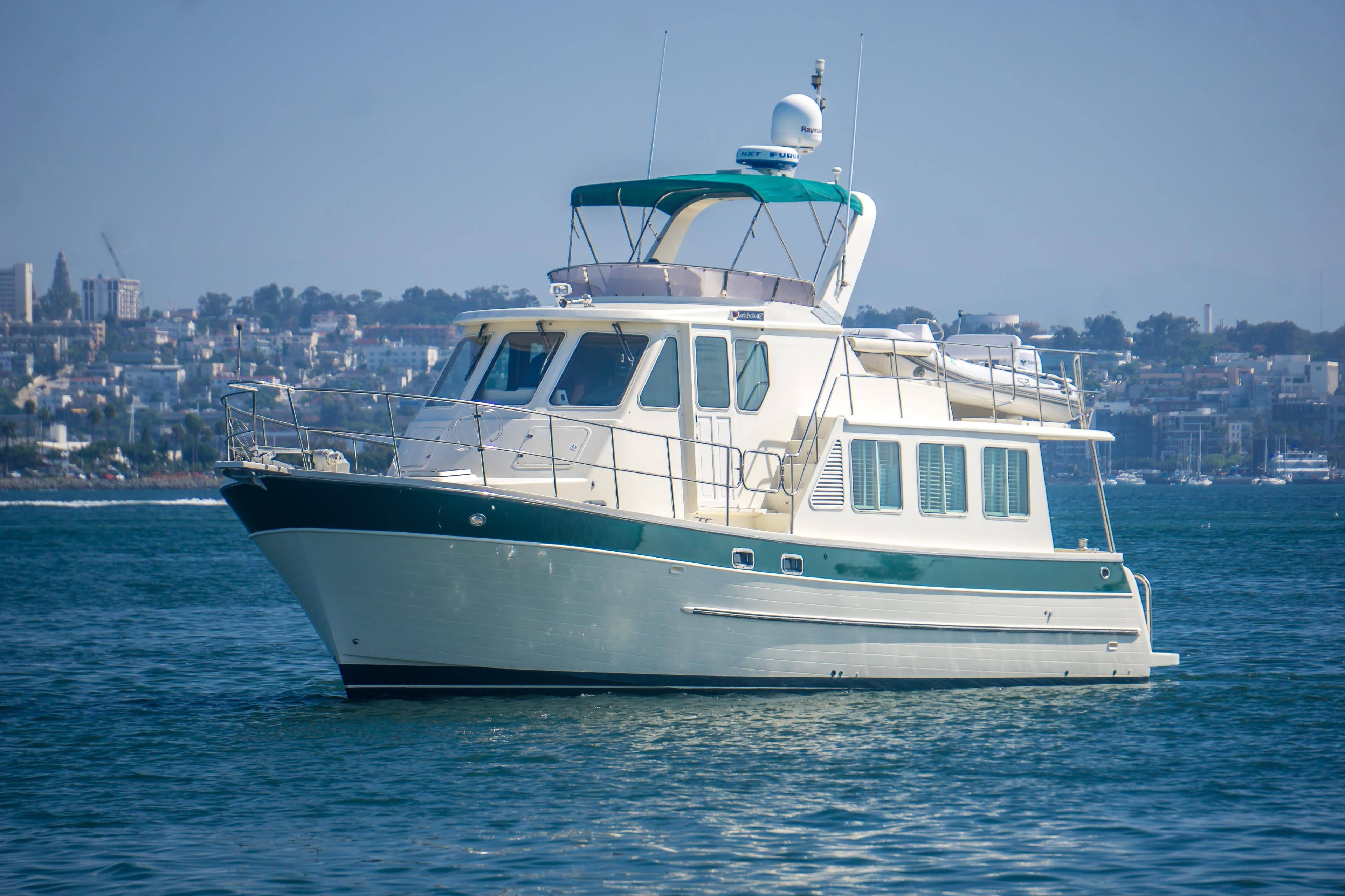 2008 North Pacific 43 Pilothouse yacht on calm water with cityscape background.