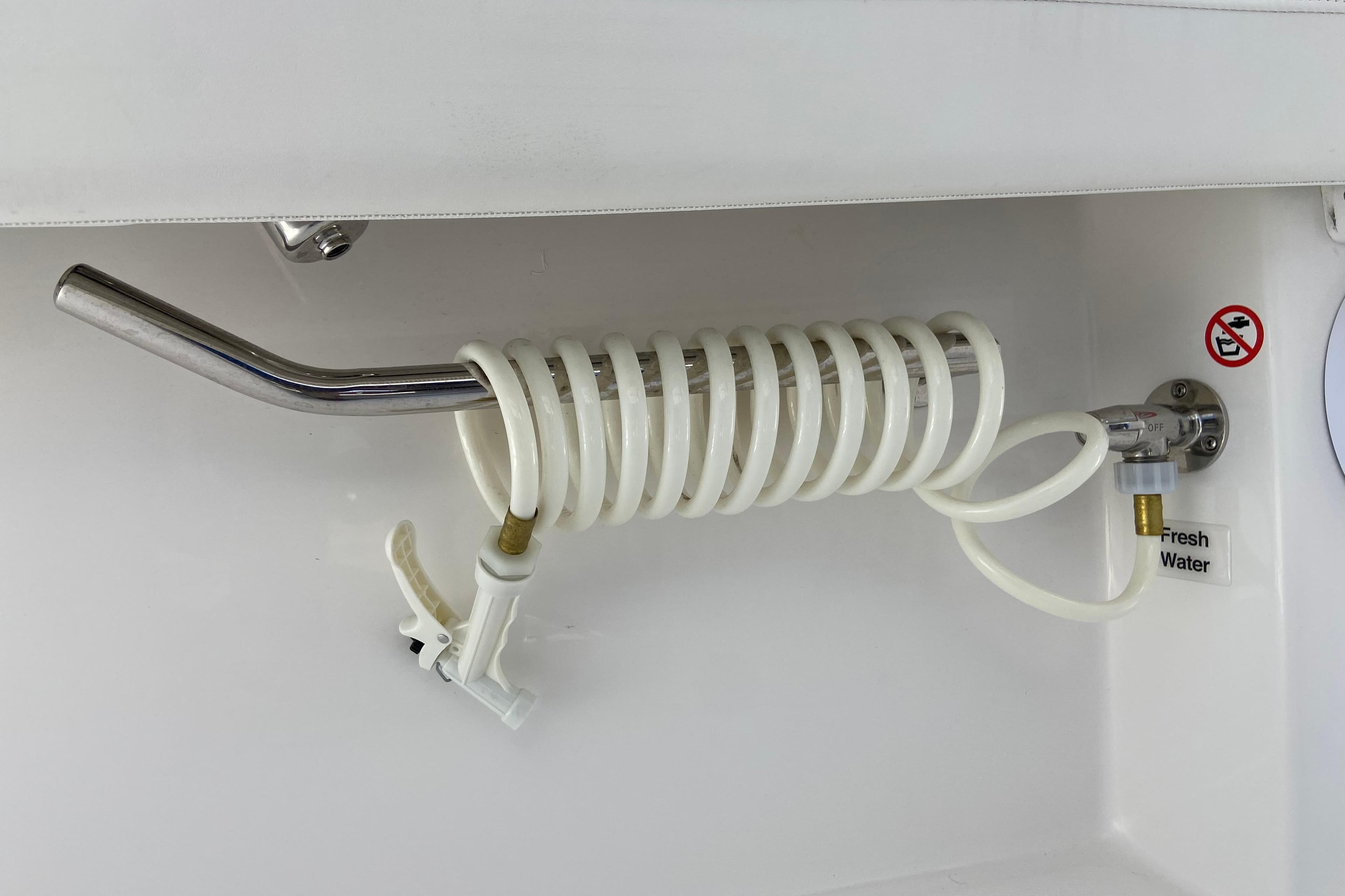 Coiled hose and faucet in 2026 Regulator 28 boat, labeled "Fresh Water."
