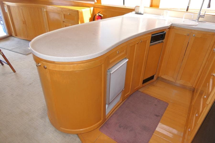 Luxurious wooden kitchen interior of 1999 Hampton 490 Pilothouse yacht with curved countertop.