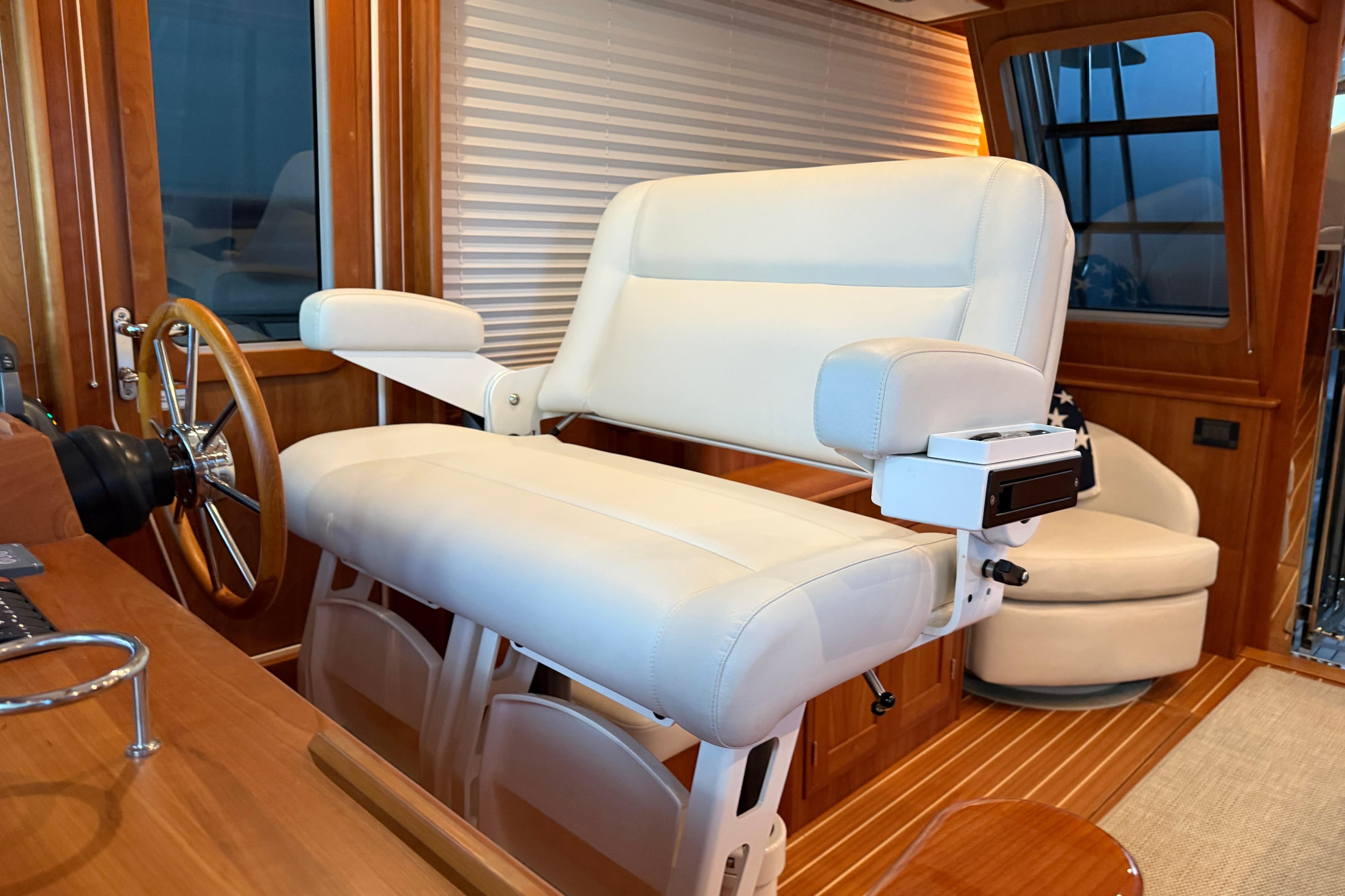 Captain's chair on 2021 Sabre 42 Fly Bridge, featuring luxurious white upholstery and wooden accents.