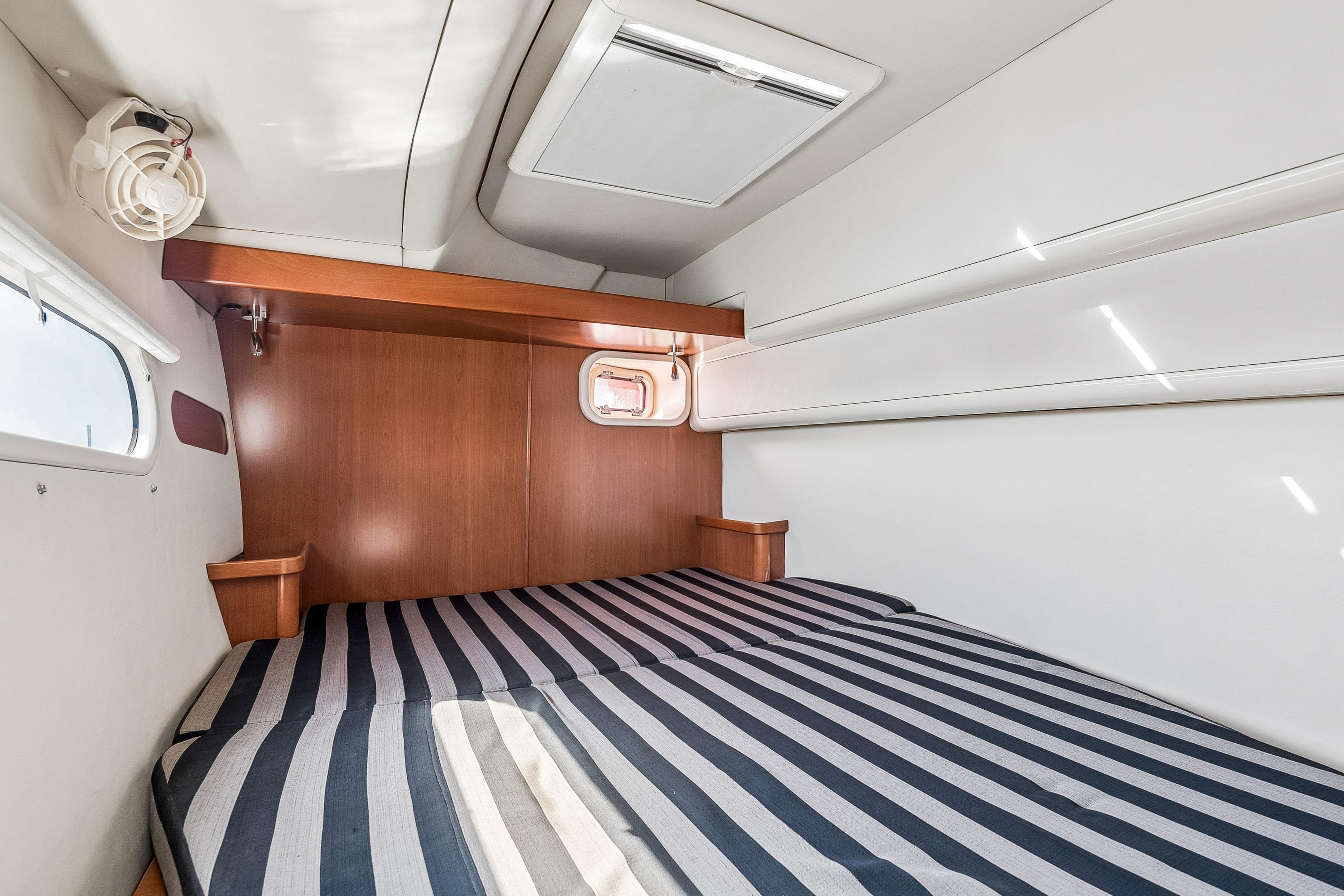 Cozy cabin interior of 2007 Leopard 46 yacht with striped bedding and wooden accents.