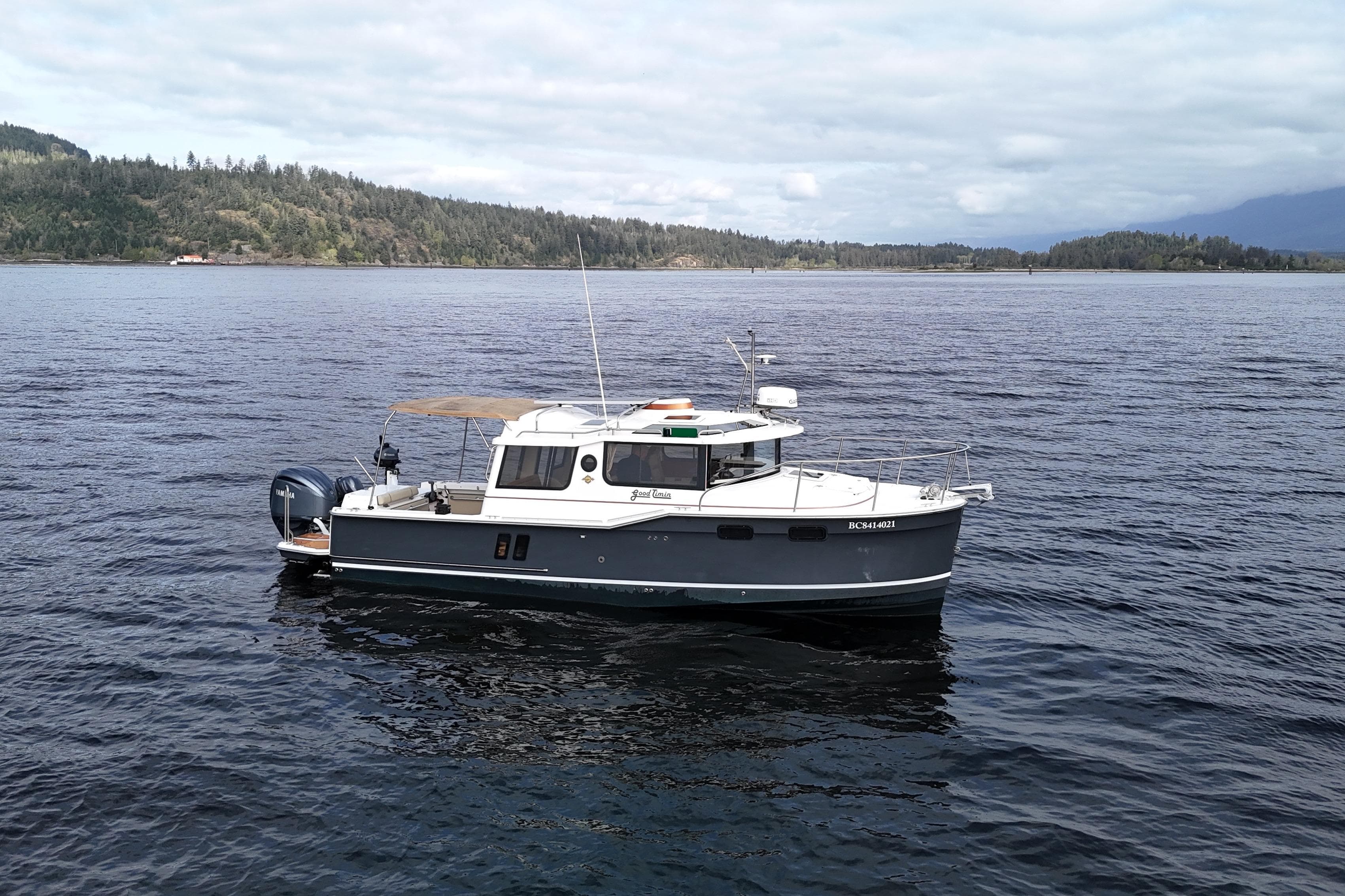 2022 Ranger Tugs R-27 boat cruising on a scenic lake with forested hills.
