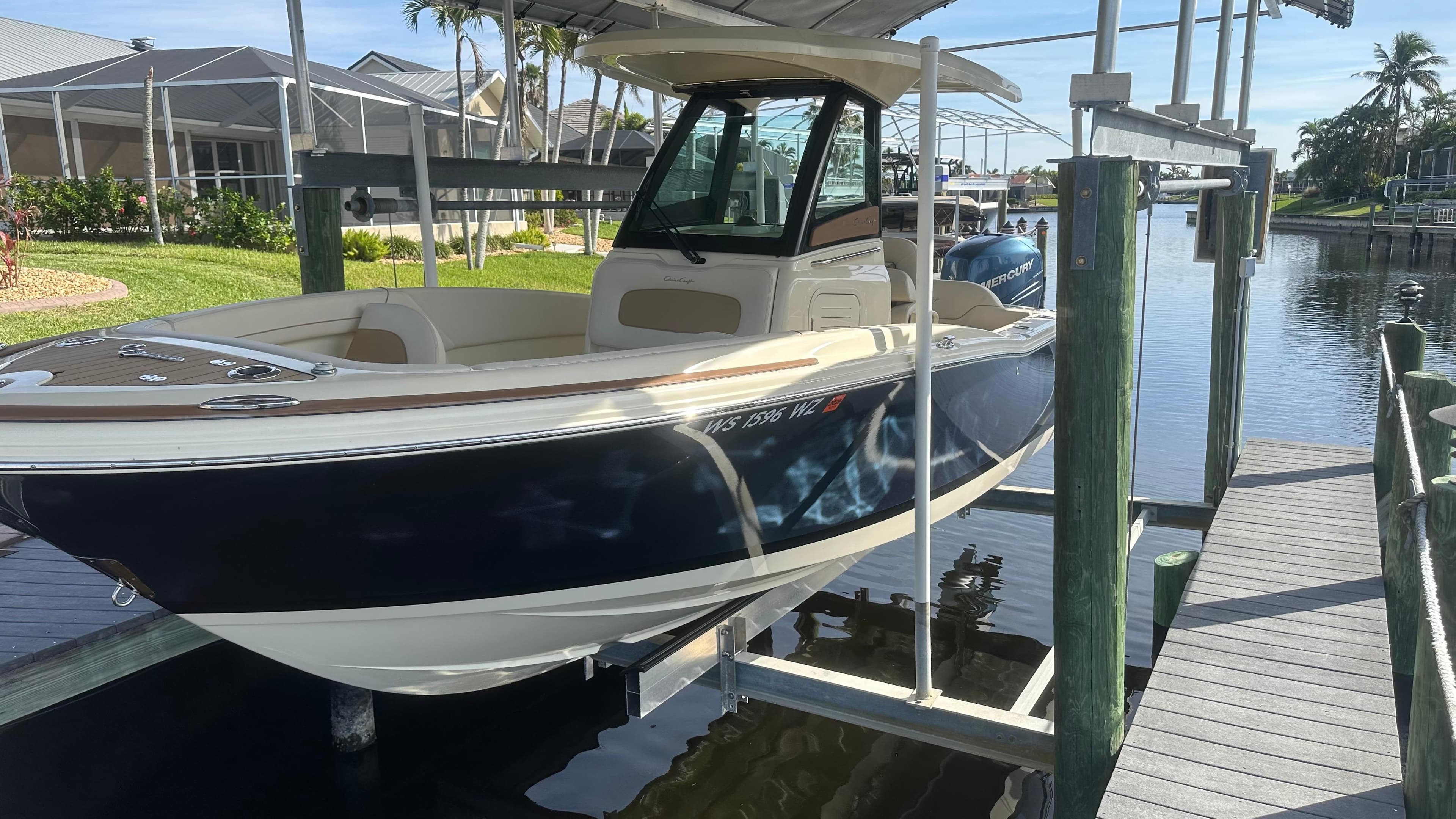 2023 Chris-Craft Catalina 24 boat on a lift by a dock, sunny day.