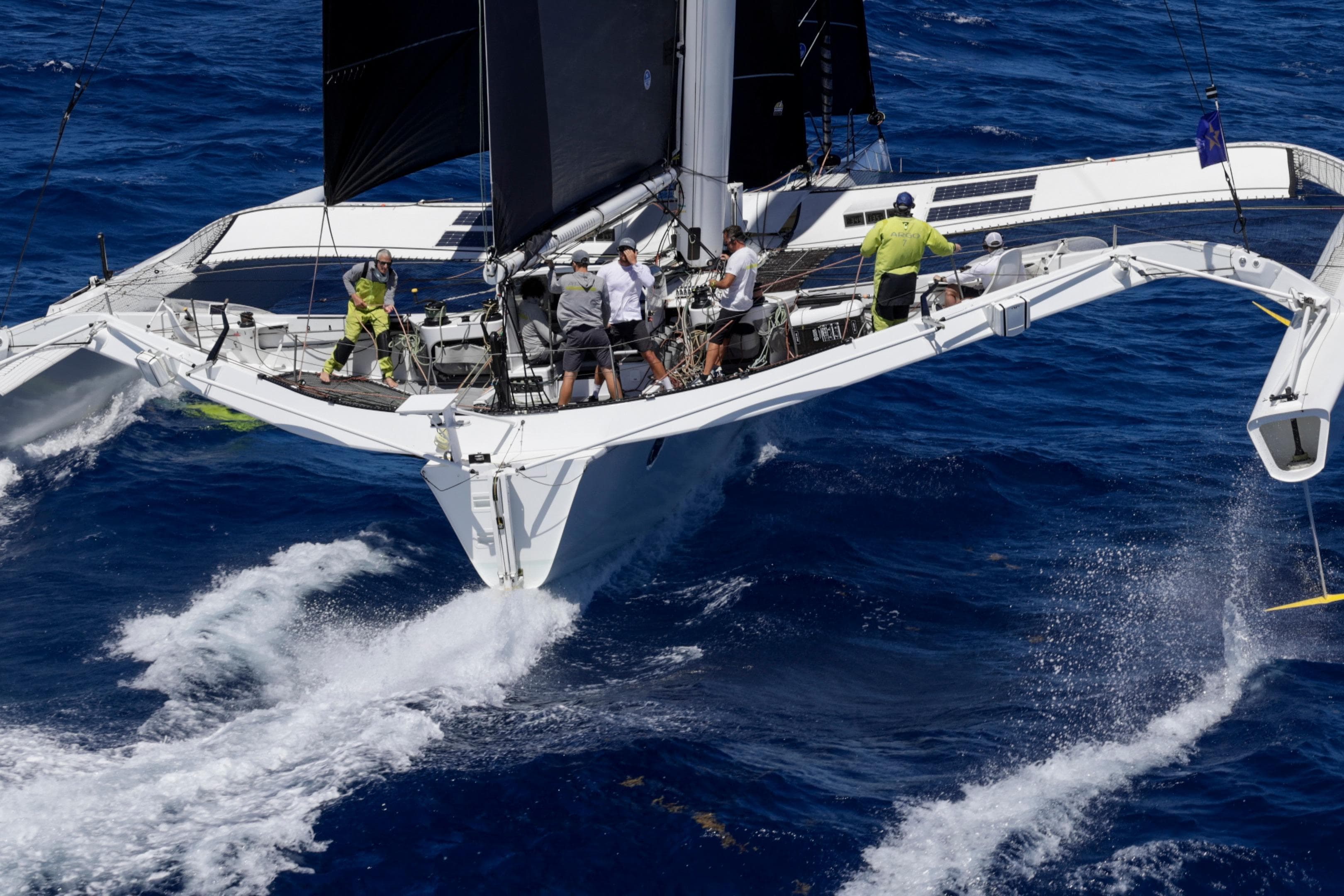 Sailing team on CDK Technologies MOD 70 trimaran, 2012, navigating ocean waves.