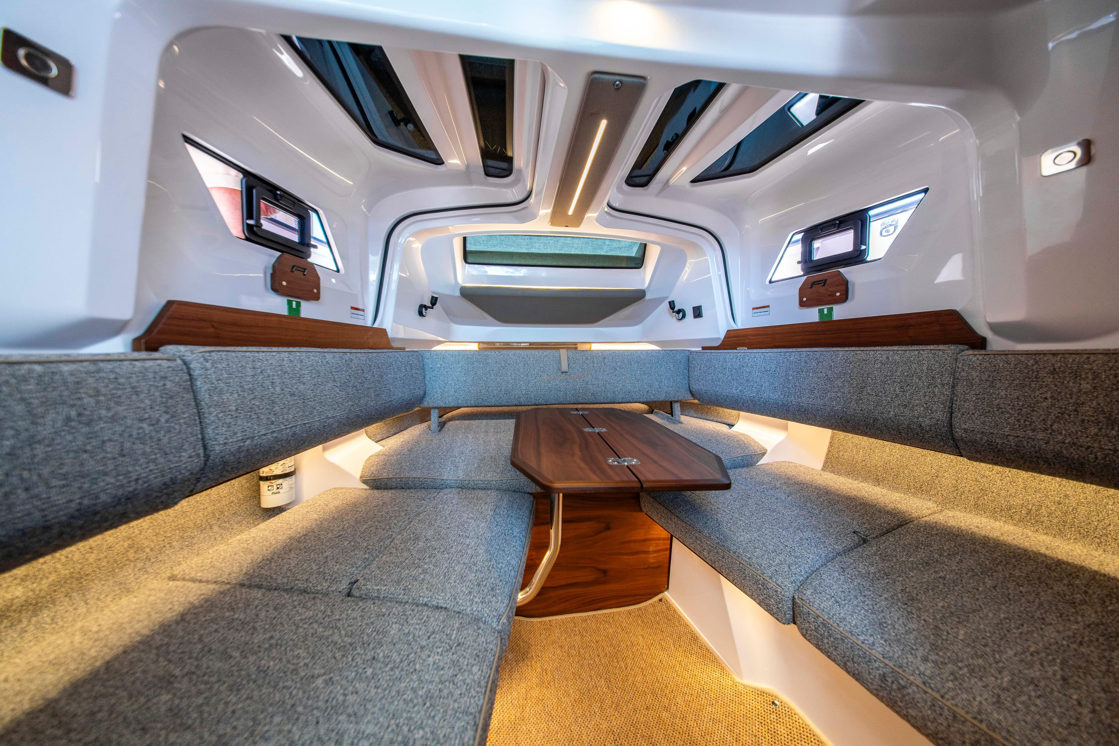 Interior of 2026 Axopar 38 Cross Cabin with modern seating and wooden table.