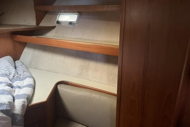 Cozy cabin interior of 1988 Kadey Krogen 42 with wooden shelves and bedding.