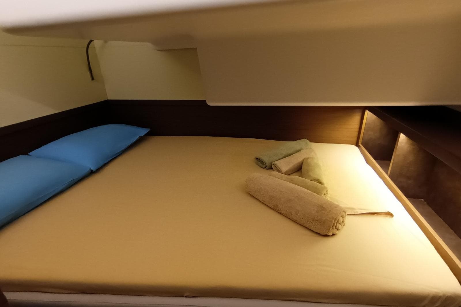 Cozy cabin interior of 2022 Lagoon 50 yacht with neatly arranged towels and pillows.