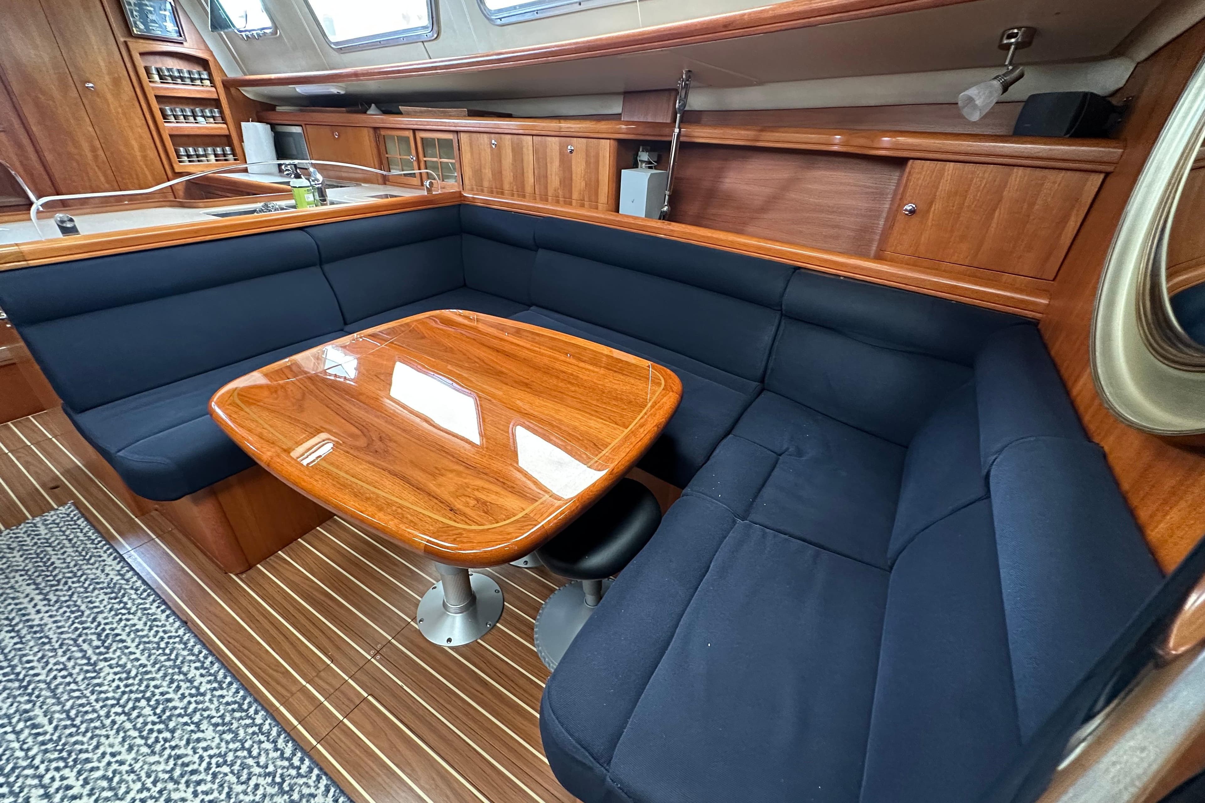 Interior of 2003 Hunter 426 Deck Salon with wooden table and navy seating.