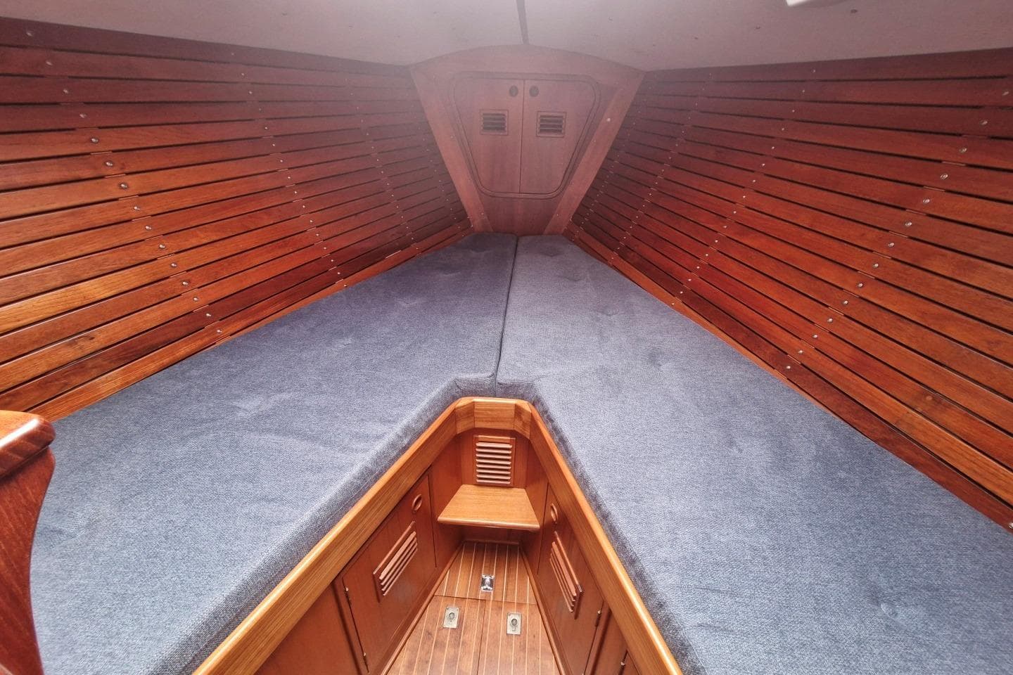 Interior of a 1976 Nautor Swan 38 sailboat with wooden paneling and blue cushions.