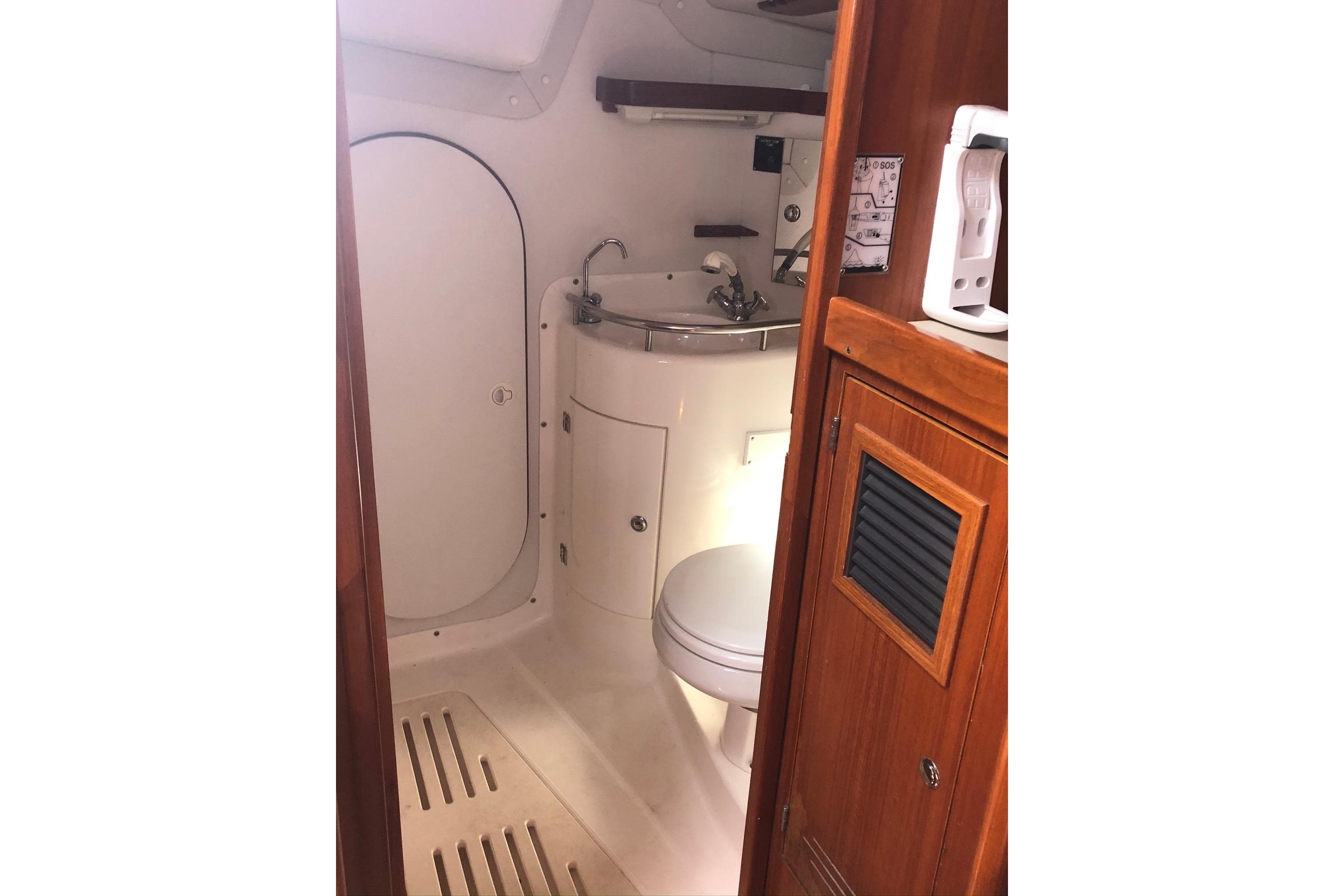 2004 J Boats J/133 yacht bathroom with sink, toilet, and wooden cabinetry.