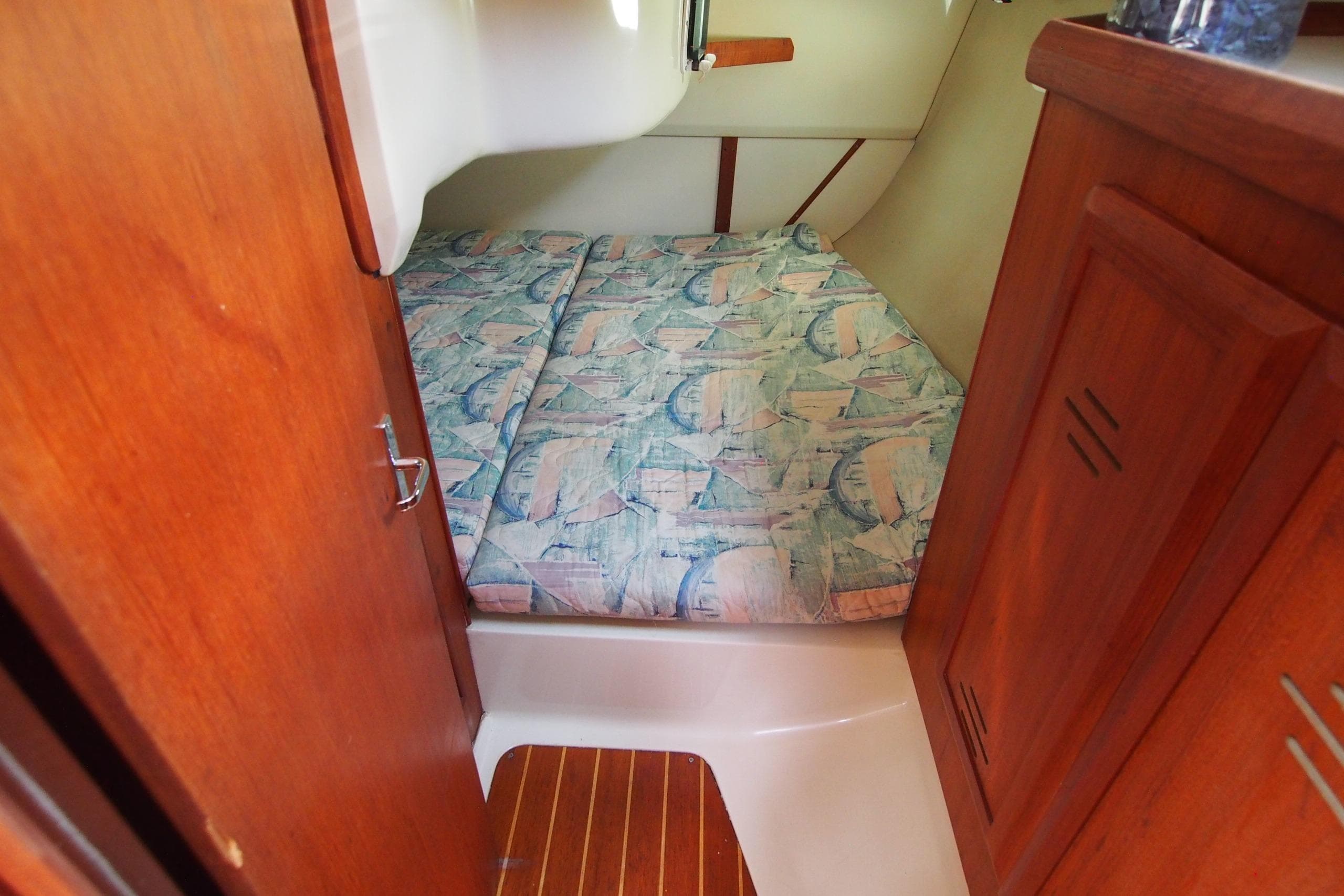Cozy cabin interior of 1995 Hunter 336 sailboat with patterned bedding and wooden accents.