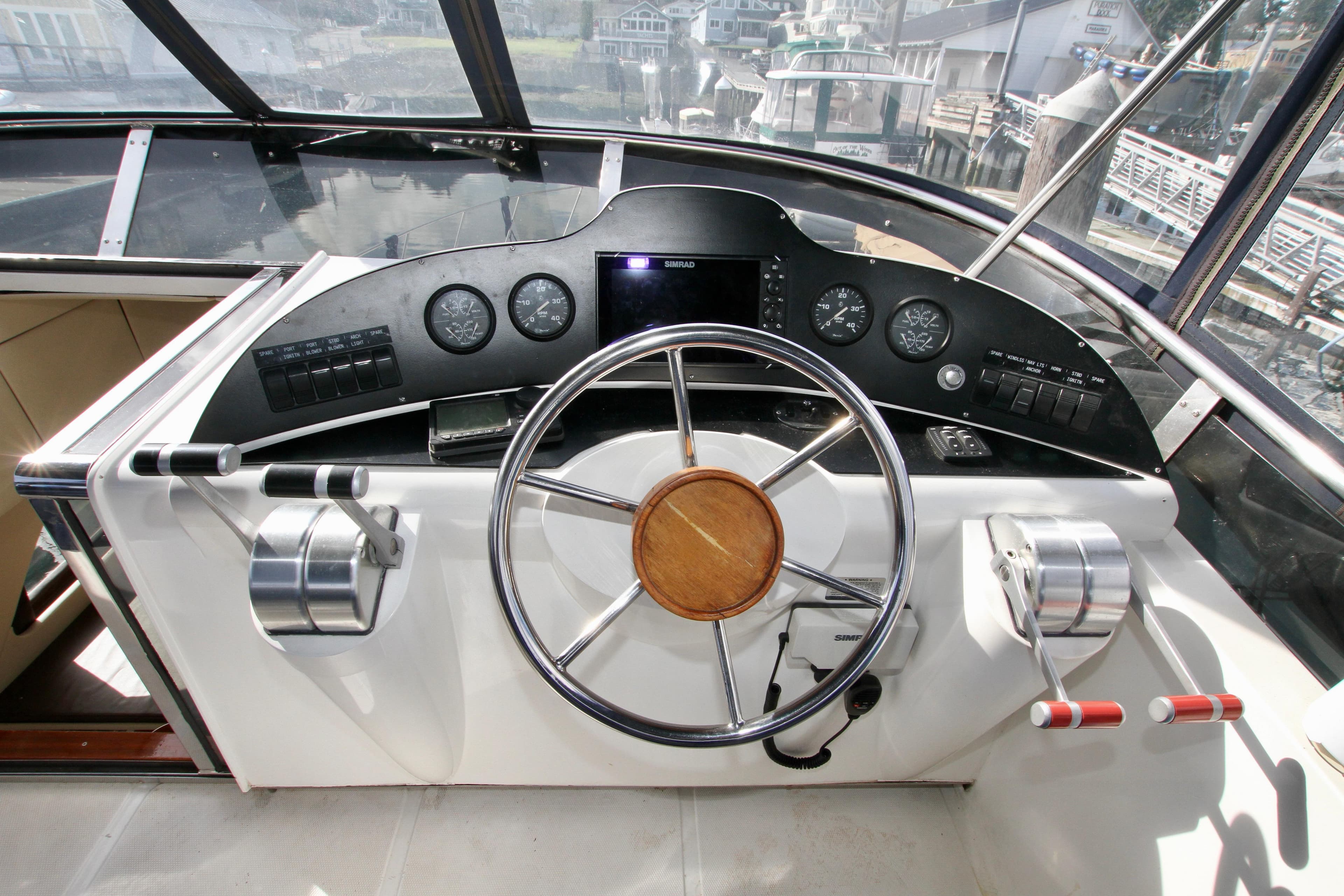 Boat cockpit with steering wheel and controls, Prima 5230, 1999 model, docked at marina.