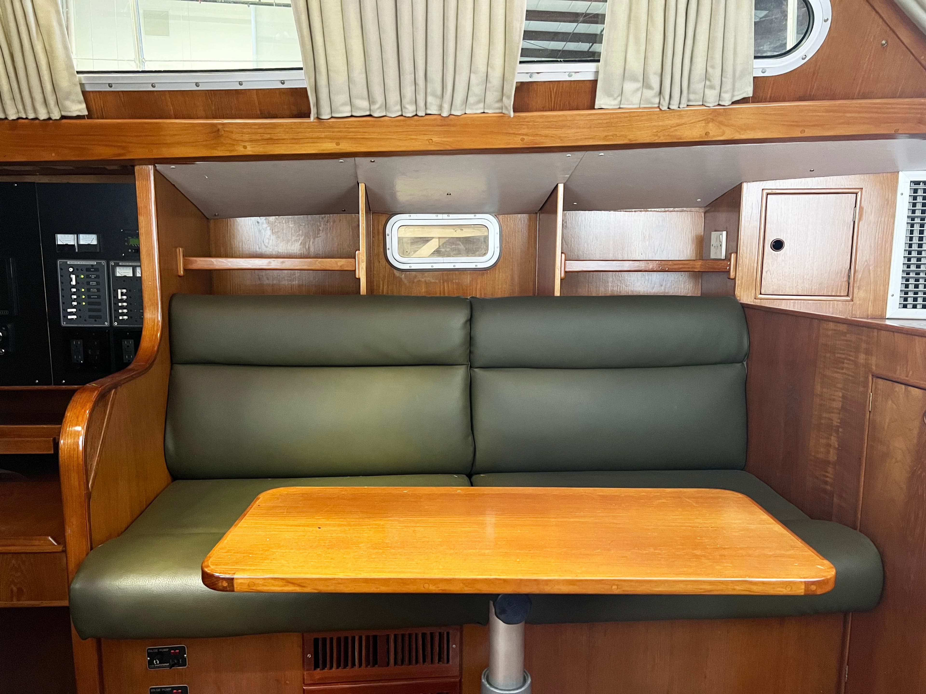 Interior of 1987 Oyster 46.5 yacht with green seating and wooden table.
