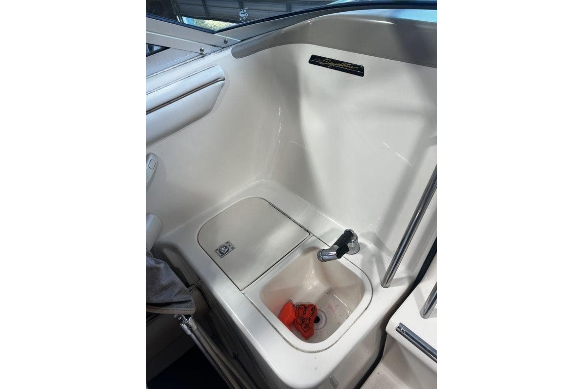 1994 Sea Ray 220 boat interior with sink and storage compartment.