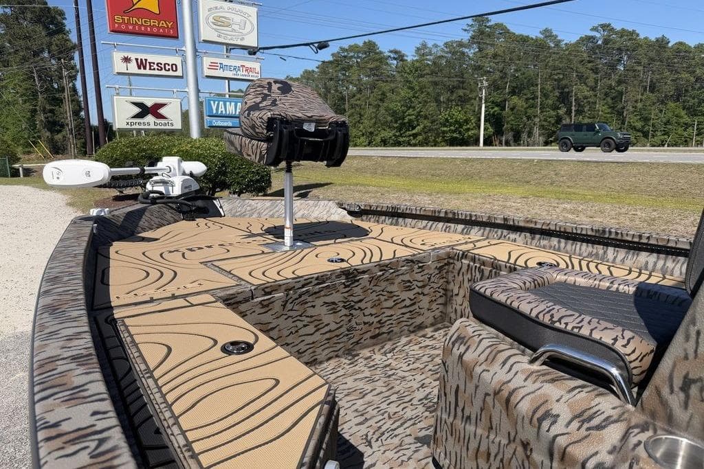 2026 Xpress H22B Bay boat with camouflage design, parked near dealership signs.