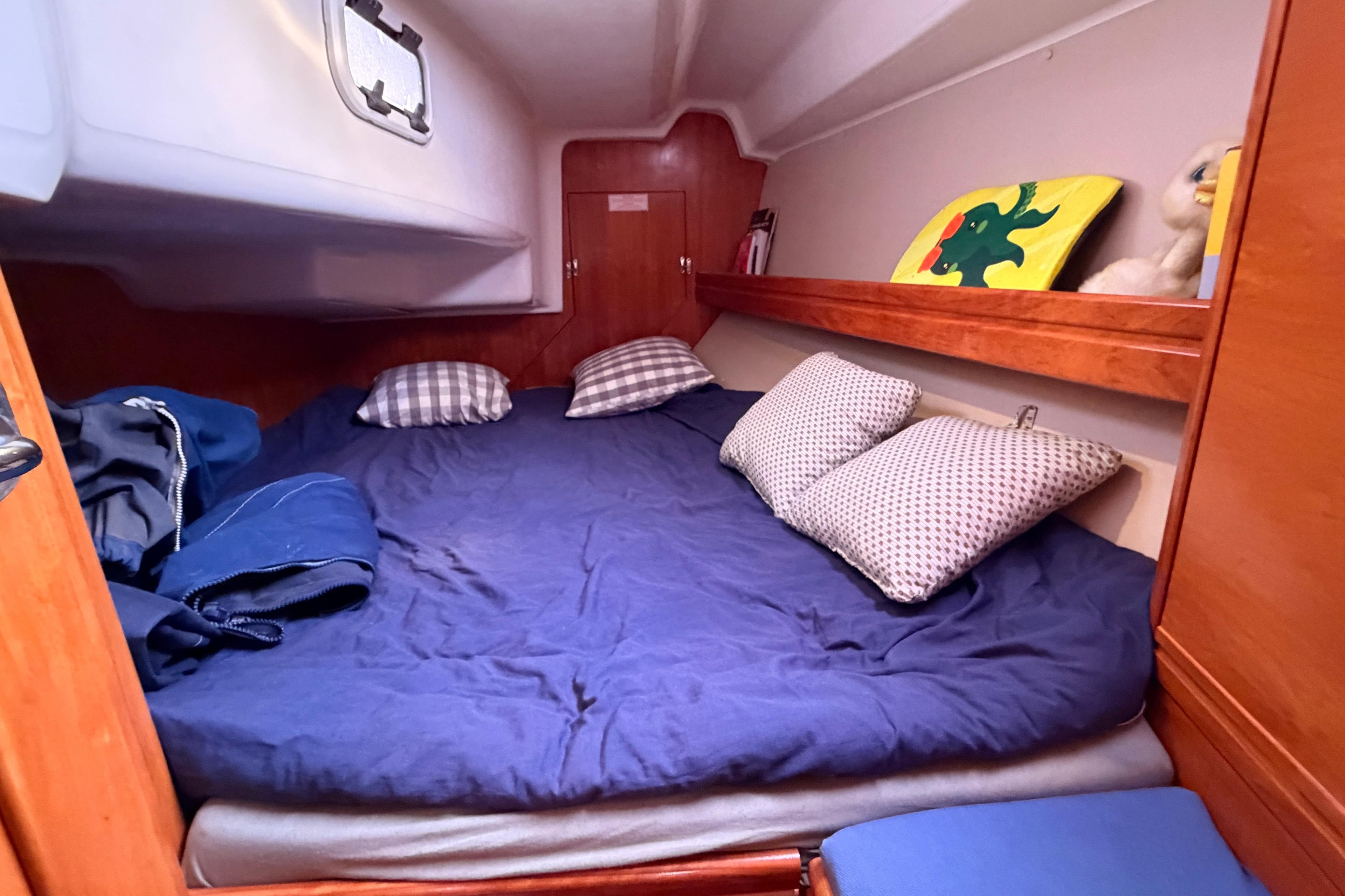 Cozy cabin interior of 2009 Bavaria 34 Cruiser yacht with blue bedding and pillows.