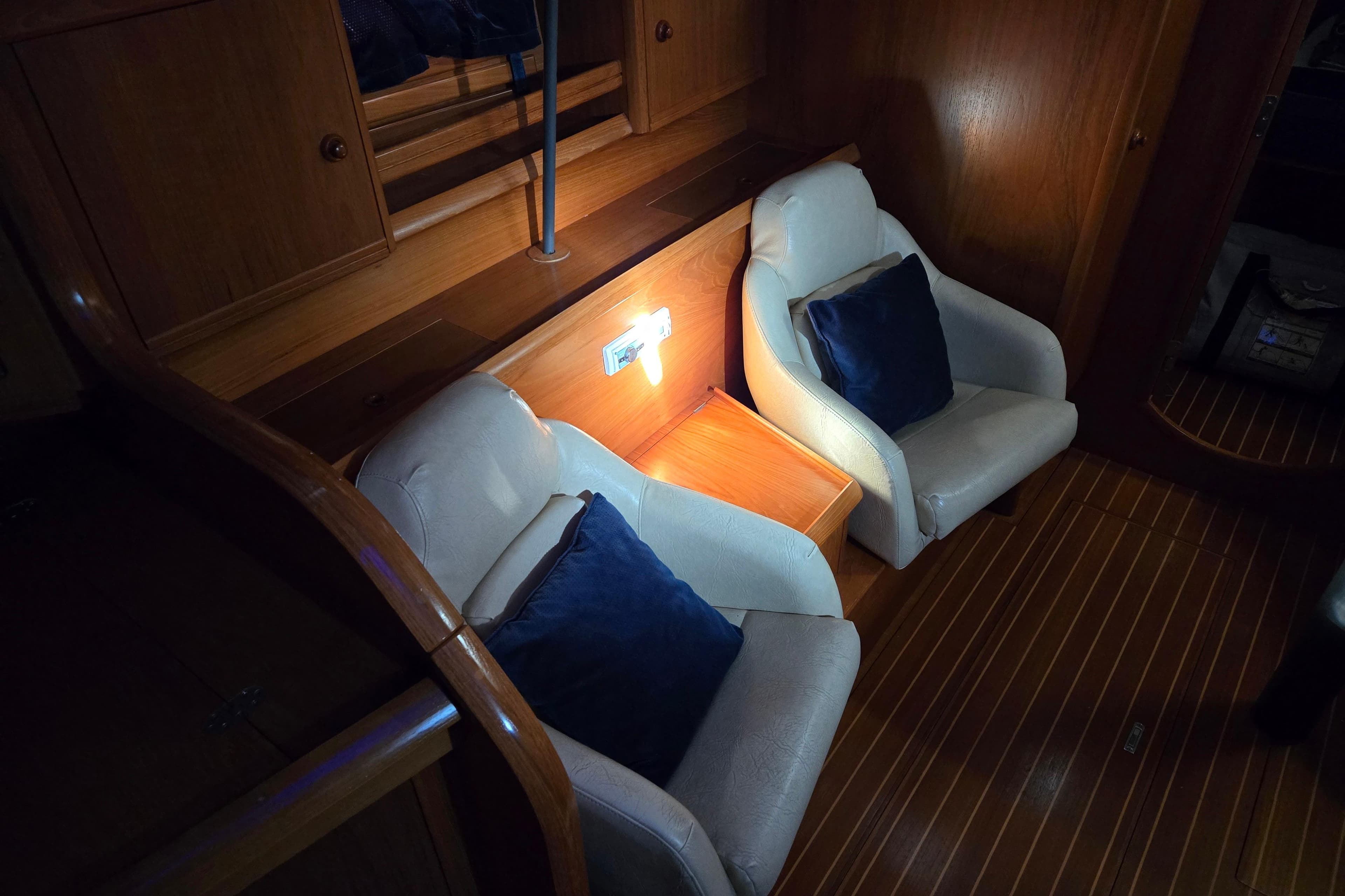 Interior of 1998 Jeanneau Sun Odyssey 42 with two chairs and wooden flooring.