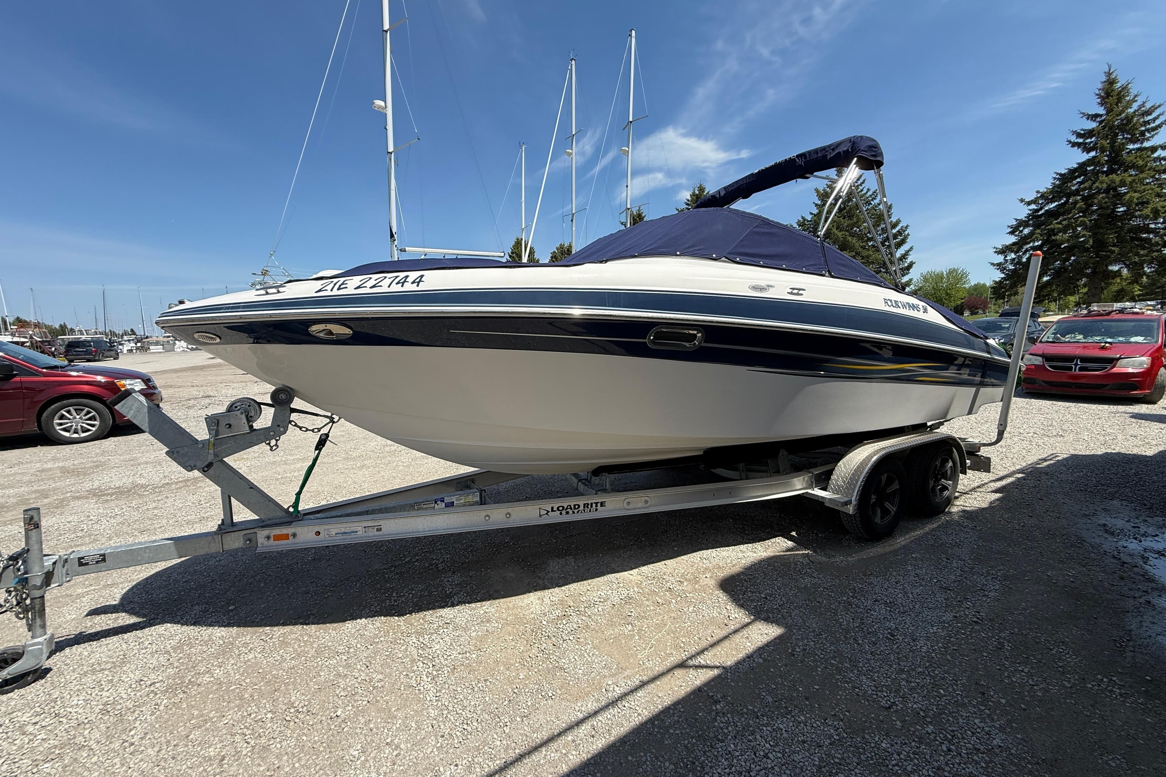 2005 Four Winns 230 Horizon boat on trailer, parked in marina lot.