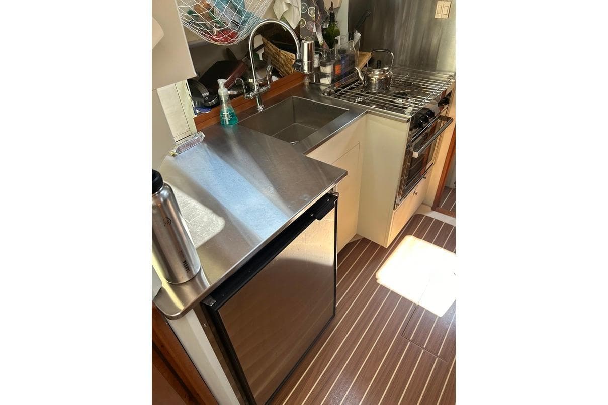 2003 Mainship Pilot 34 Sedan galley with stainless steel sink, compact fridge, and stove.