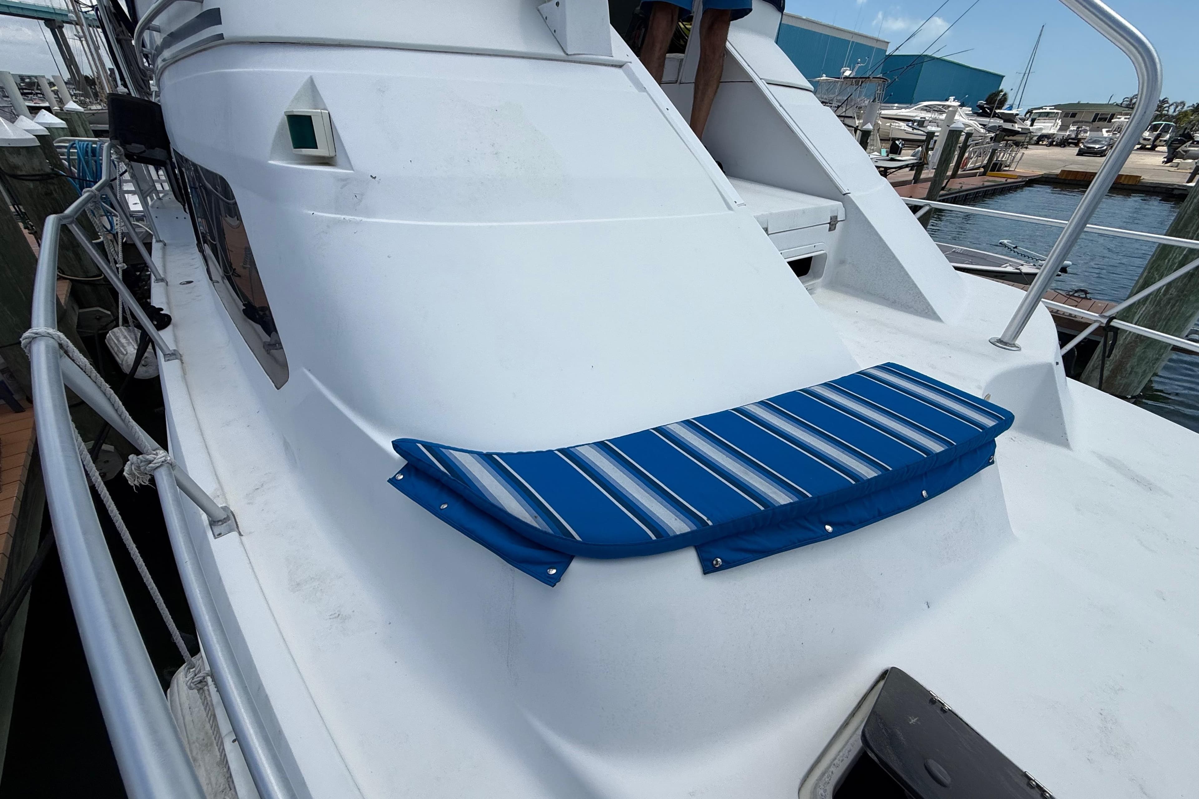1995 Mainship 37 Motor Yacht with blue-striped cushion on deck, docked at marina.