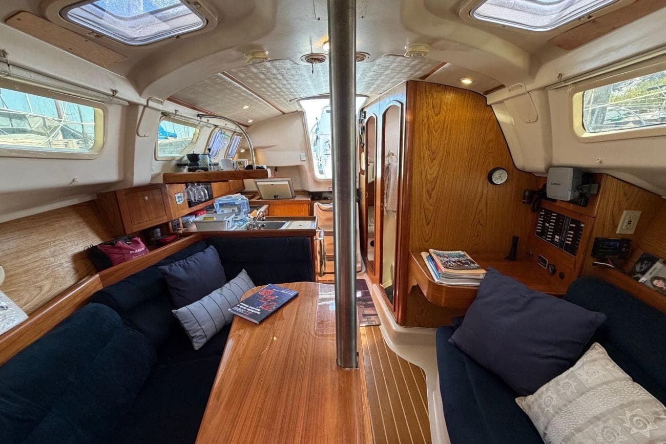 Interior of a 2001 Hunter 320 sailboat, featuring cozy seating and wooden cabinetry.