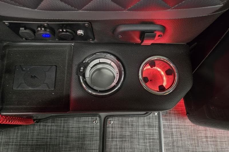 2026 AquaPatio 235 DFL interior console with cup holders and controls, illuminated in red.